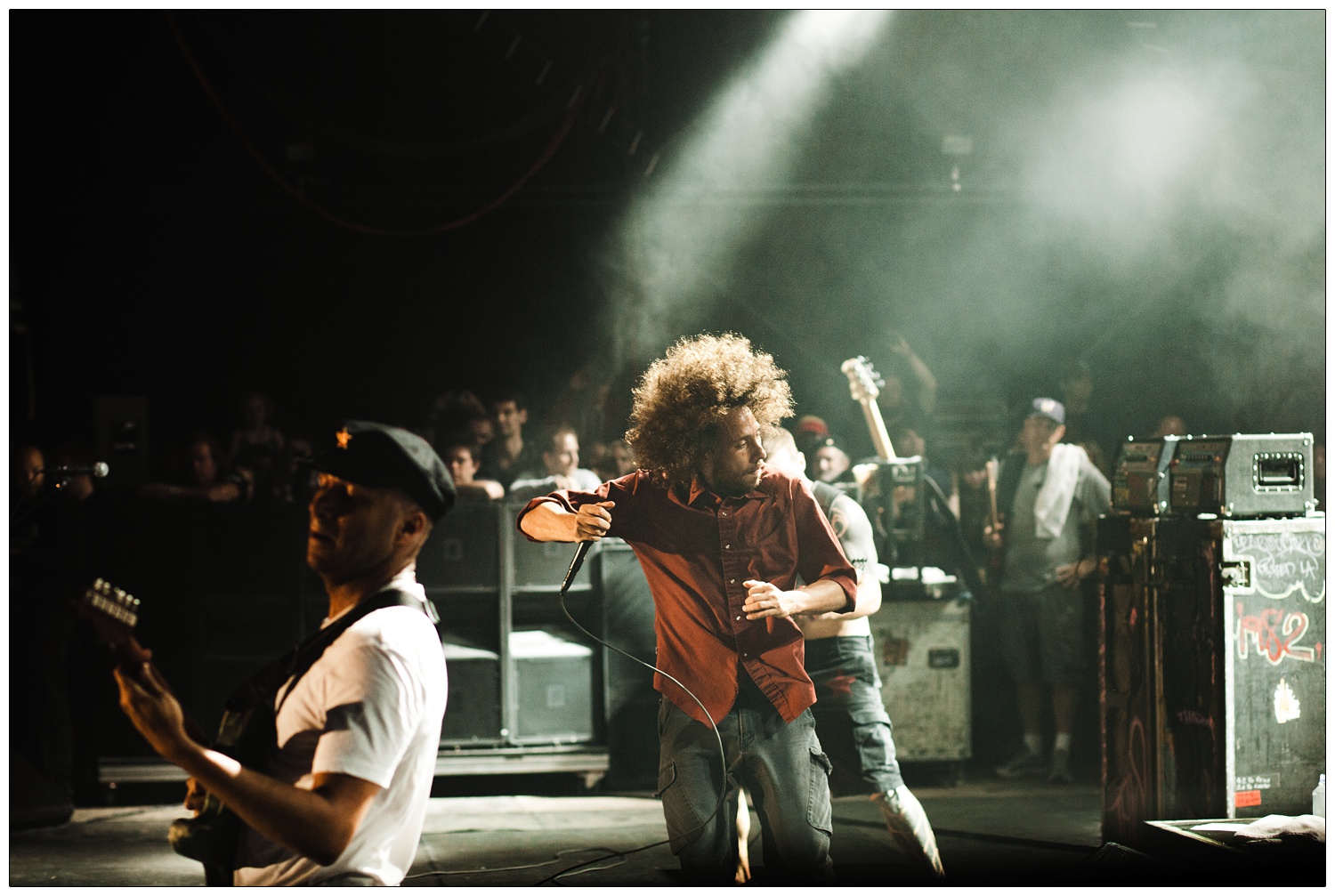 Action shot of Zack de la Rocha, Tom Morello and Tim Commerford on stage in 2010 in London. Onlookers from the side of stage.