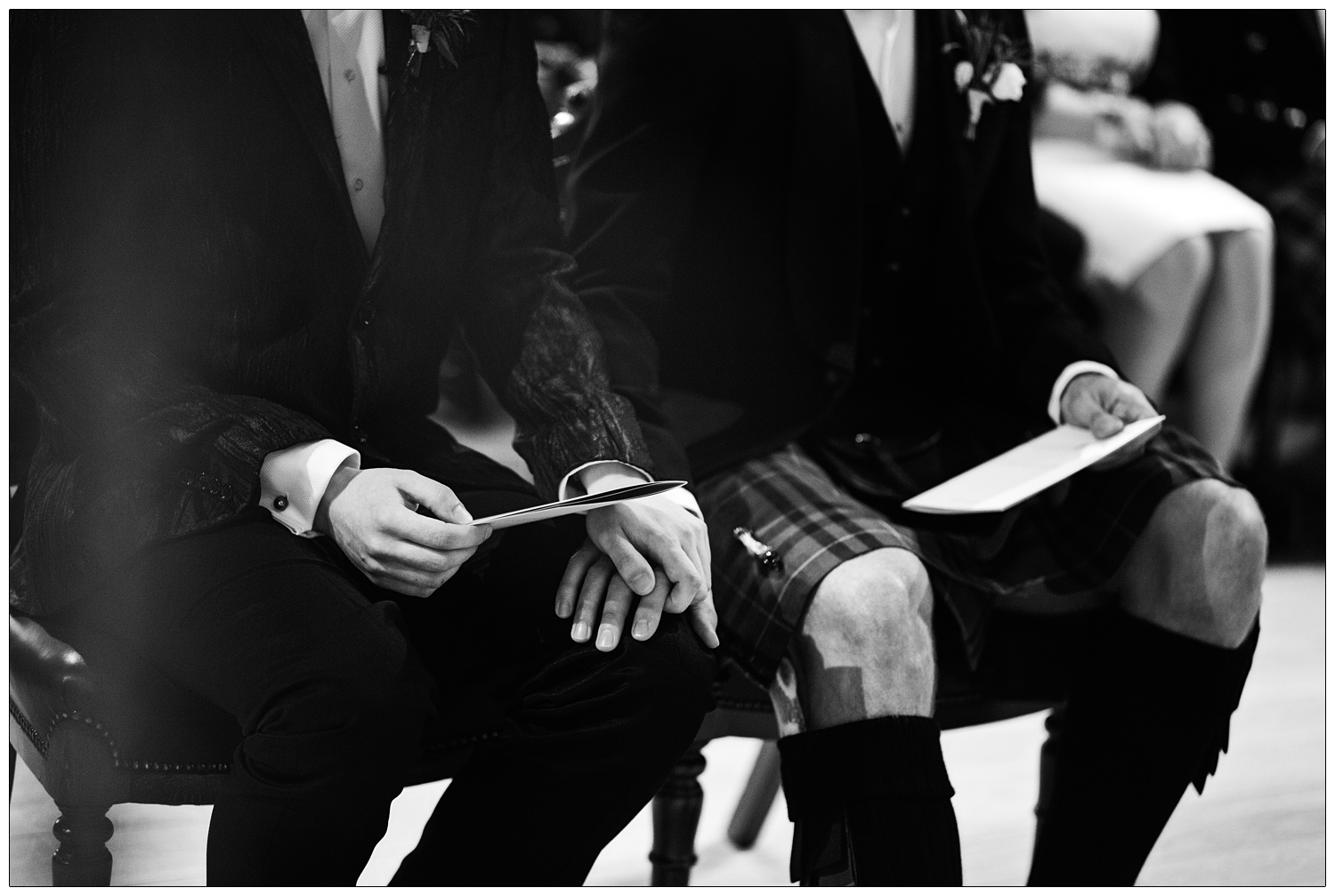 A man in a kilt puts his hand on the knee of his husband.