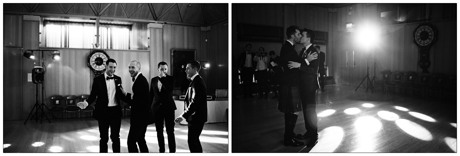 Men kiss during the first dance. There are round lights on the floor.