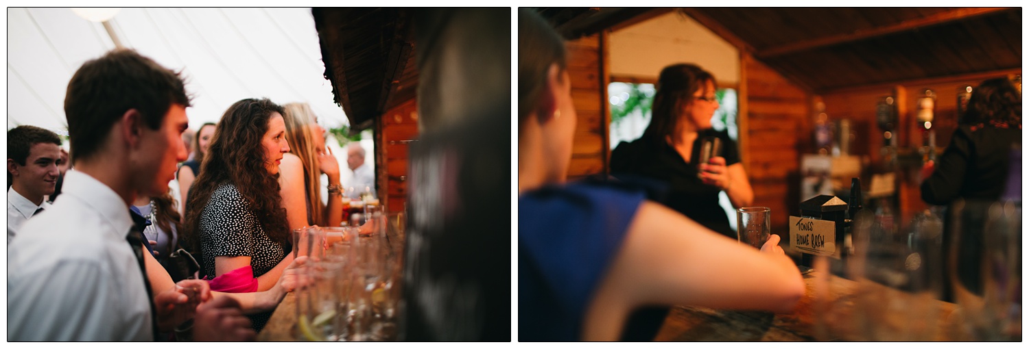 People waiting at a bar inside a shed inside a marquee at a wedding.