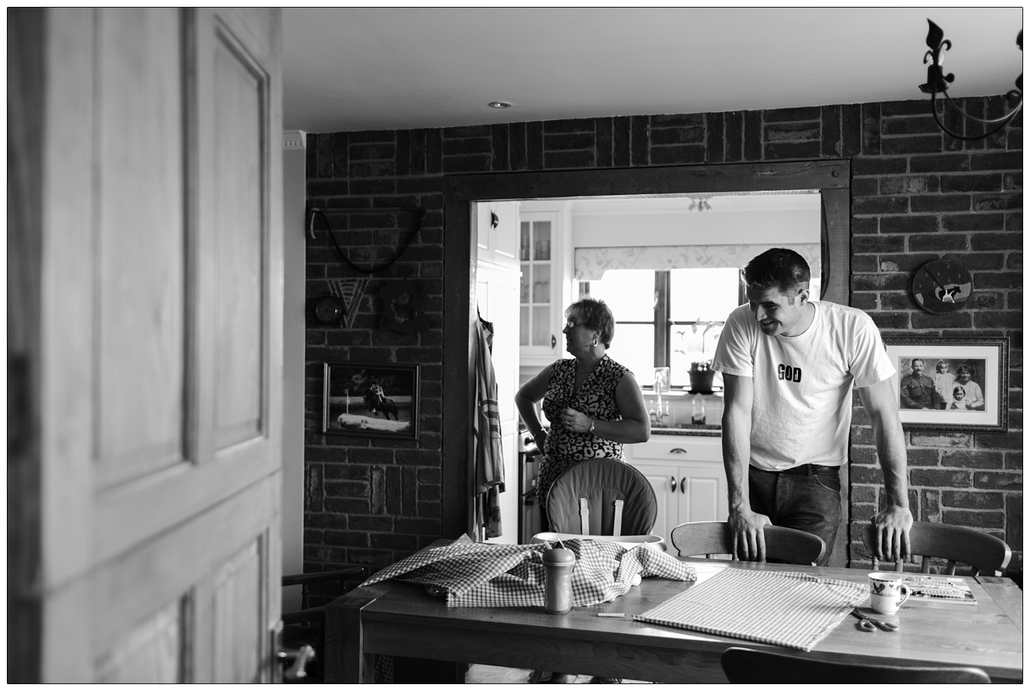 Man with hands on back of a chair in a kitchen.