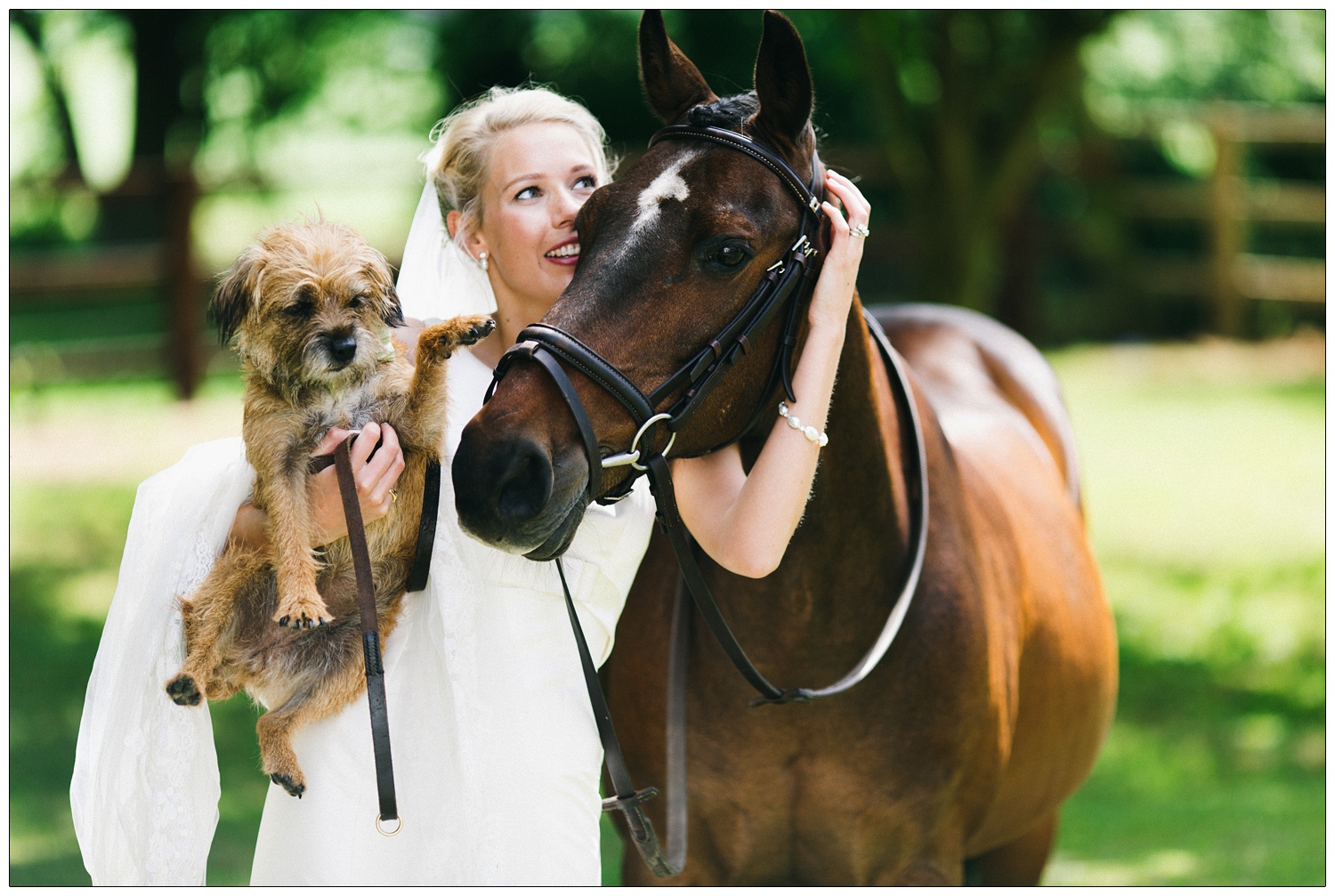 The bride holds her dog while hugging her horse.