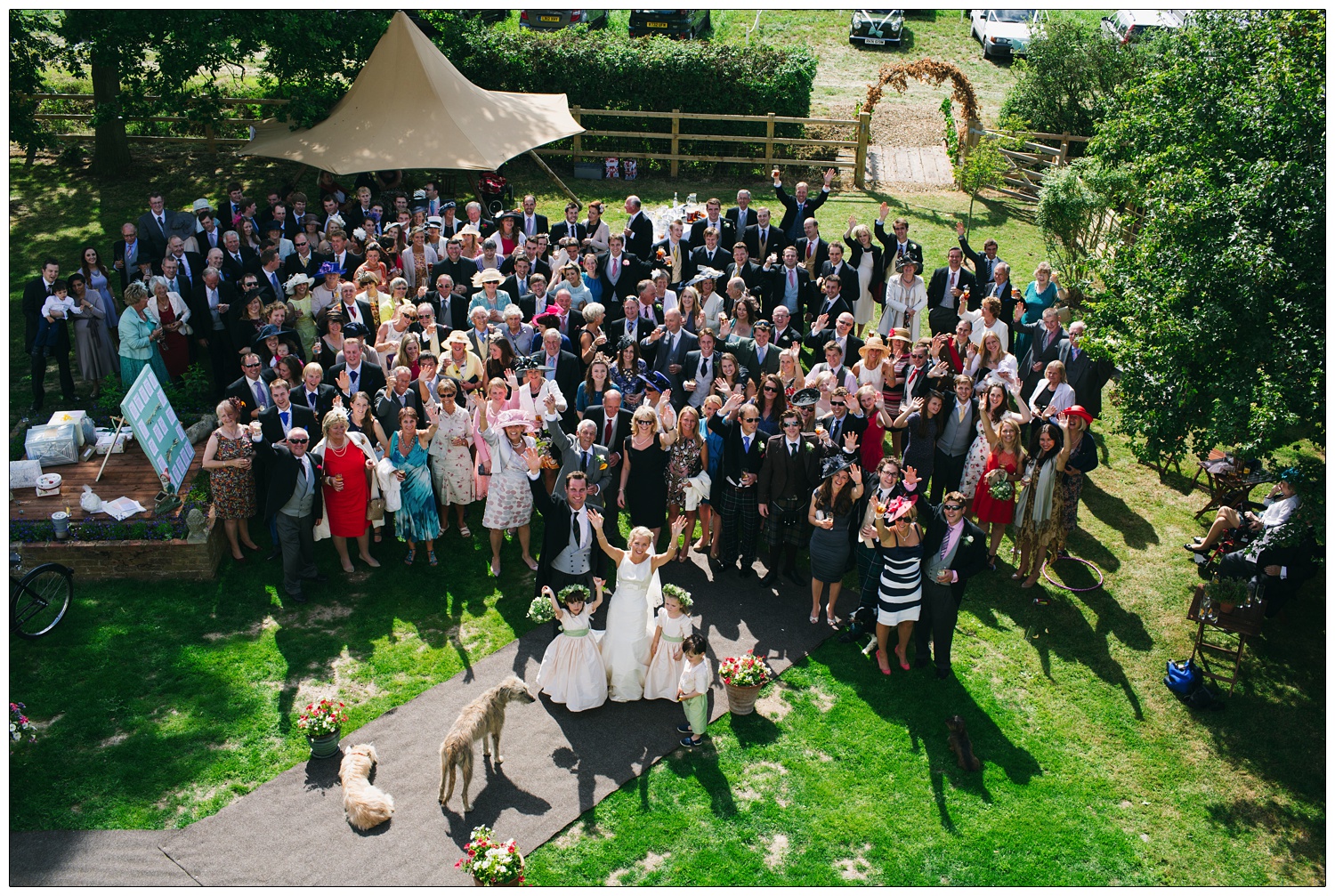 A photograph of all the wedding guests taken from a bedroom window looking down. The people are waving, the dogs are in the picture too.