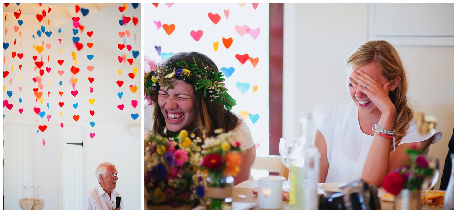 Father of the bride gives a speech, strings of colourful hearts hang from the ceiling.