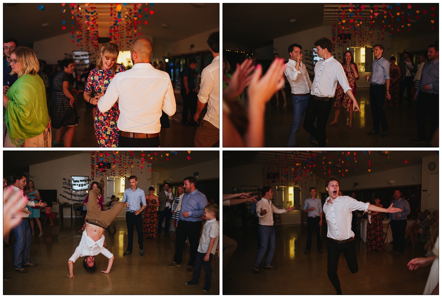 A man does a handstand on the dance floor at a wedding. There are strings of hearts hanging from the ceiling.