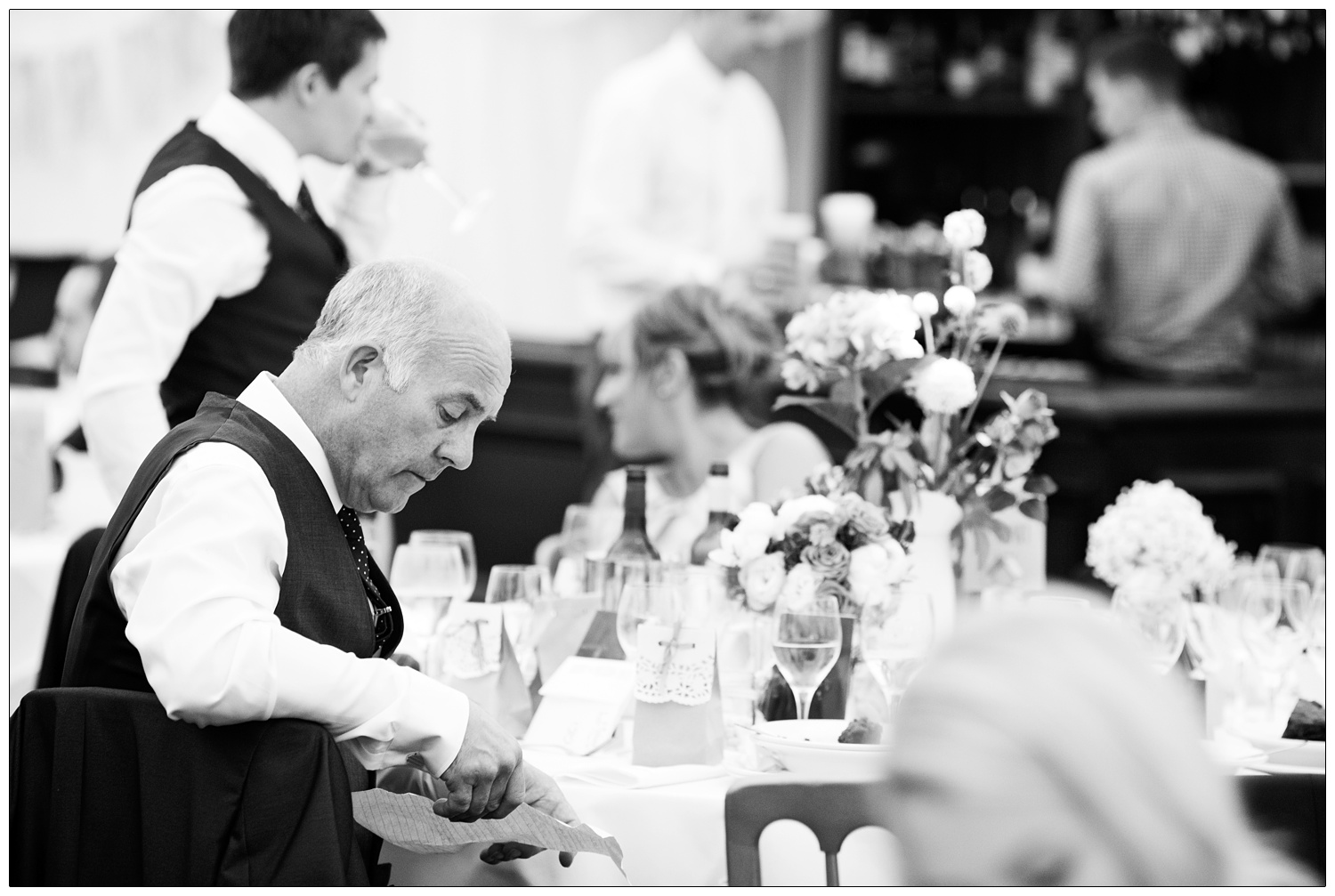 The father of the bride checks his speech over while he sits at a table.