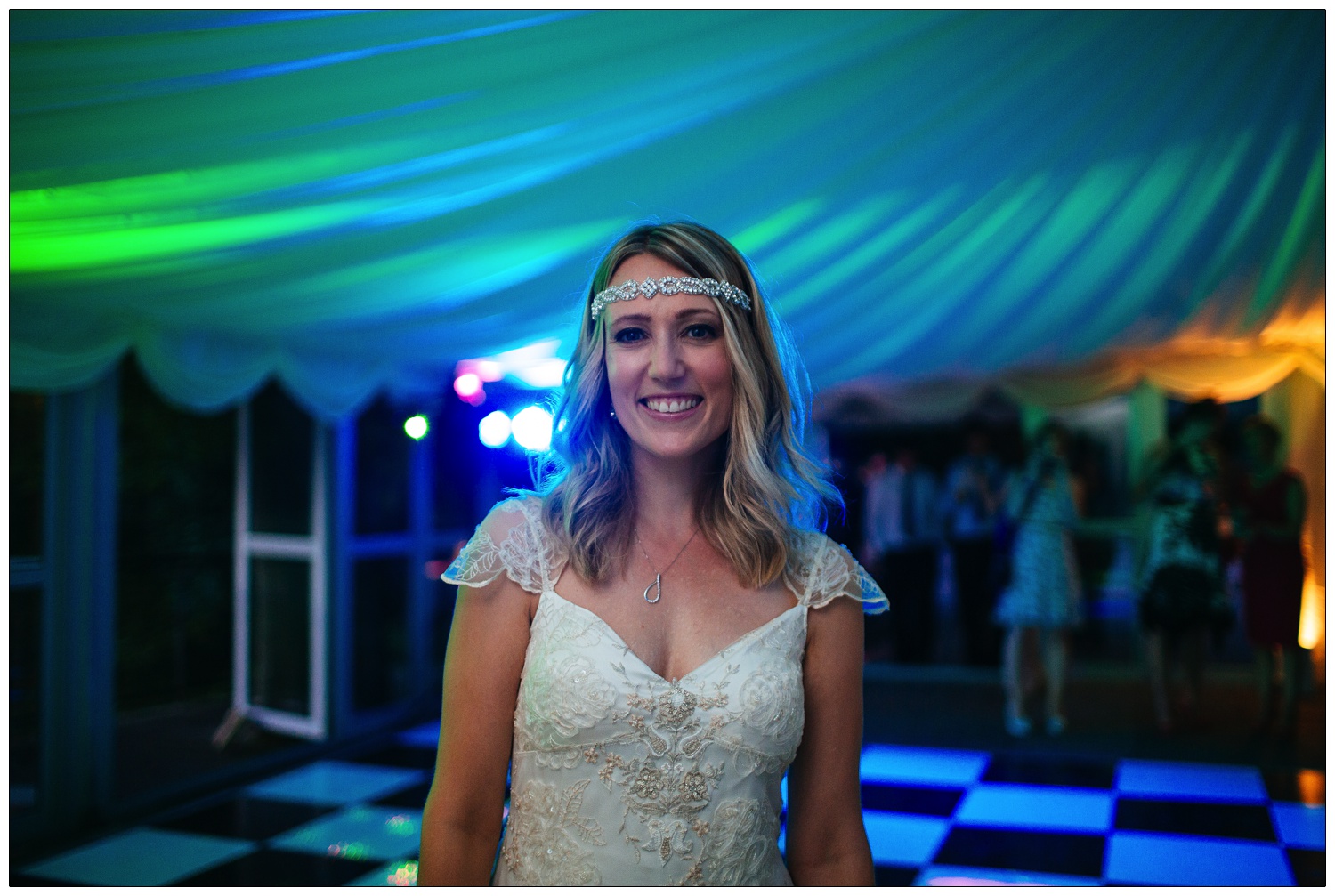 The bride is smiling at the camera. The dance floor is lit up blue.