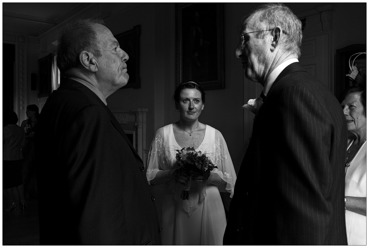 A bride looks at her dad talking to a man in The Assembly Room at Tenterden Town Hall.