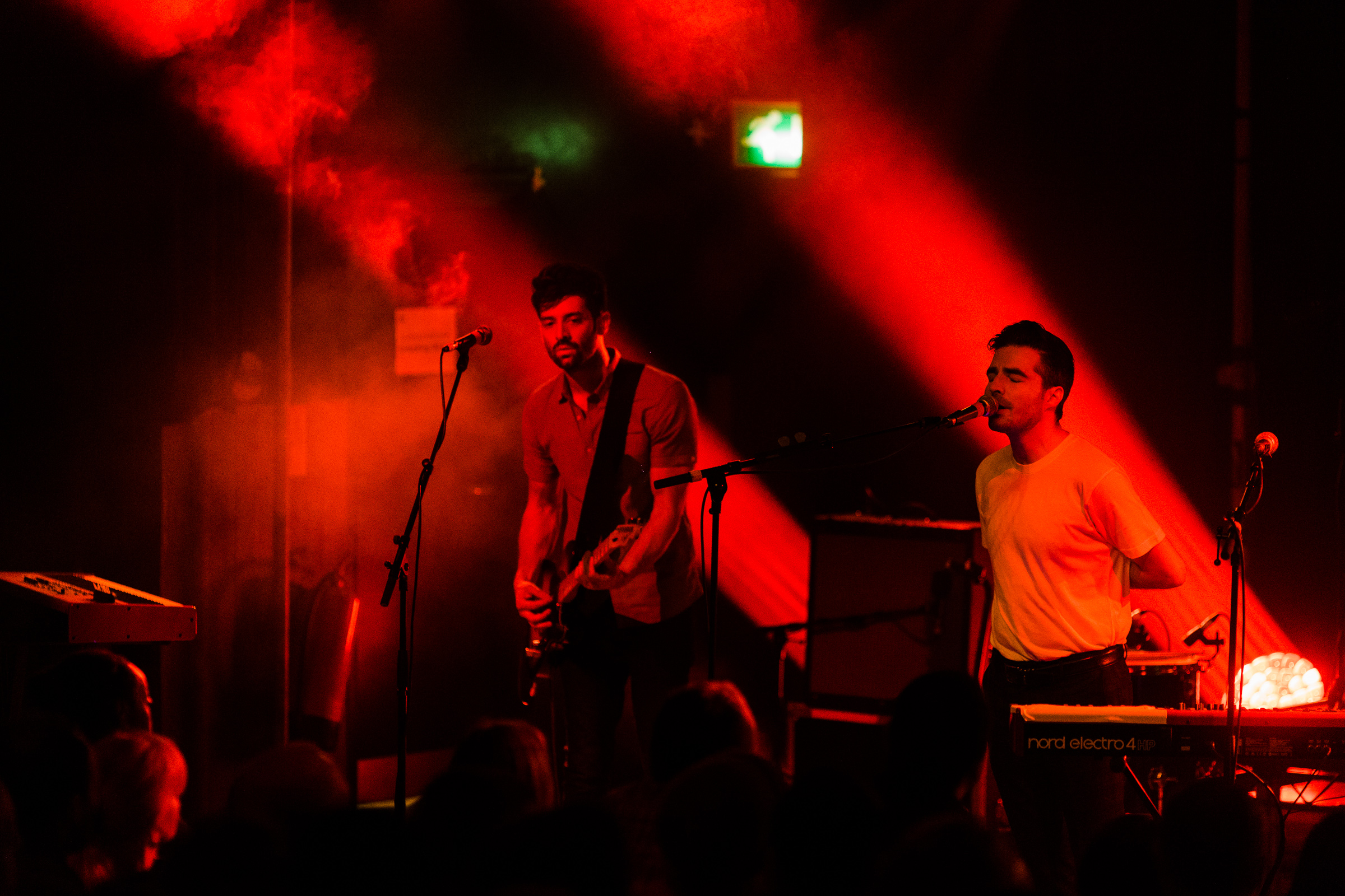 Andrew Smith and Nathan Nicholson of The Boxer Rebellion on stage at Scala in 2014. The lighting is red and some of the audience can be seen.