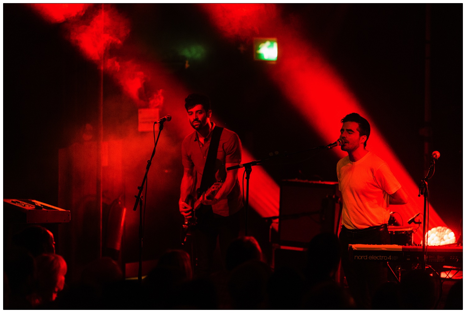 Andrew Smith and Nathan Nicholson of The Boxer Rebellion on stage at Scala in 2014. The lighting is red and some of the audience can be seen.