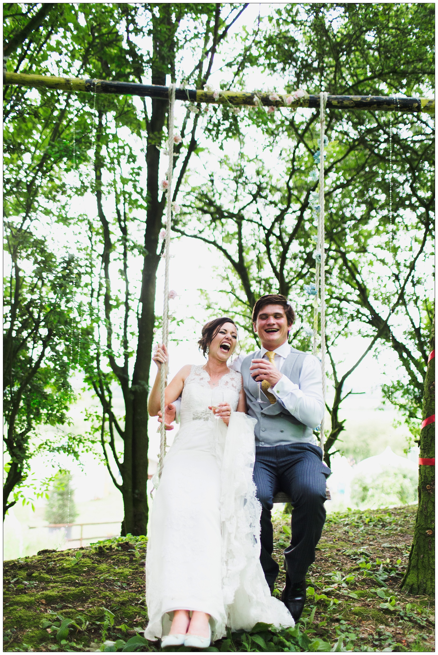 The bride and groom are laughing. They are sat on a swing in the trees. The wedding is in Stow Maries near South Woodham Ferrers.