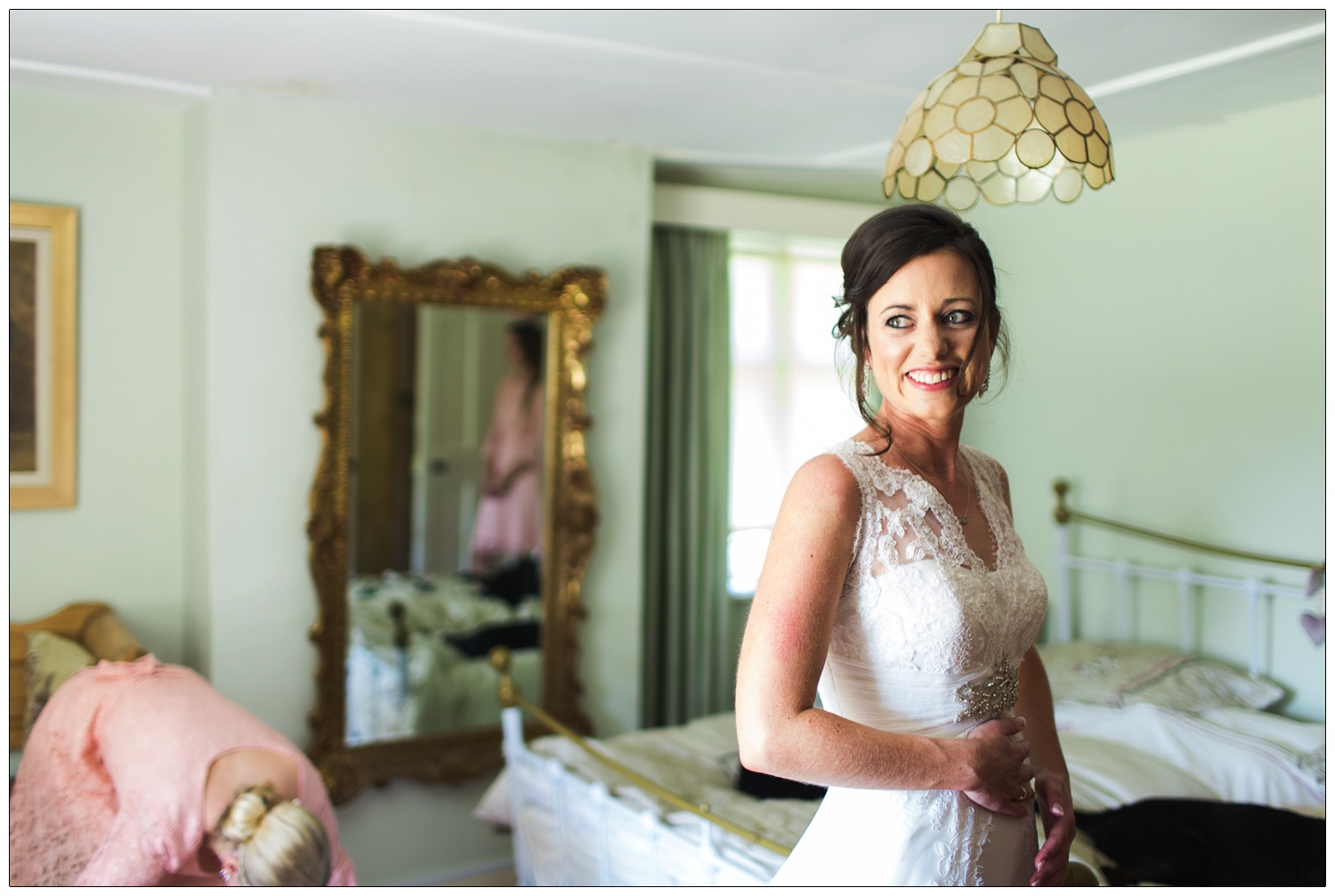 The bride in a bedroom looking out to a window.