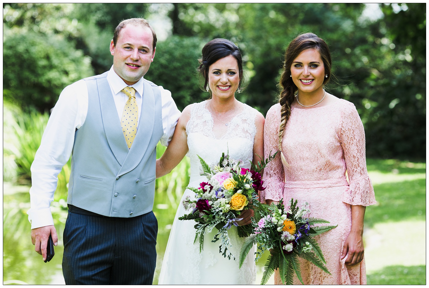 Siblings on a wedding day. In the family home garden, the bride is in the middle.