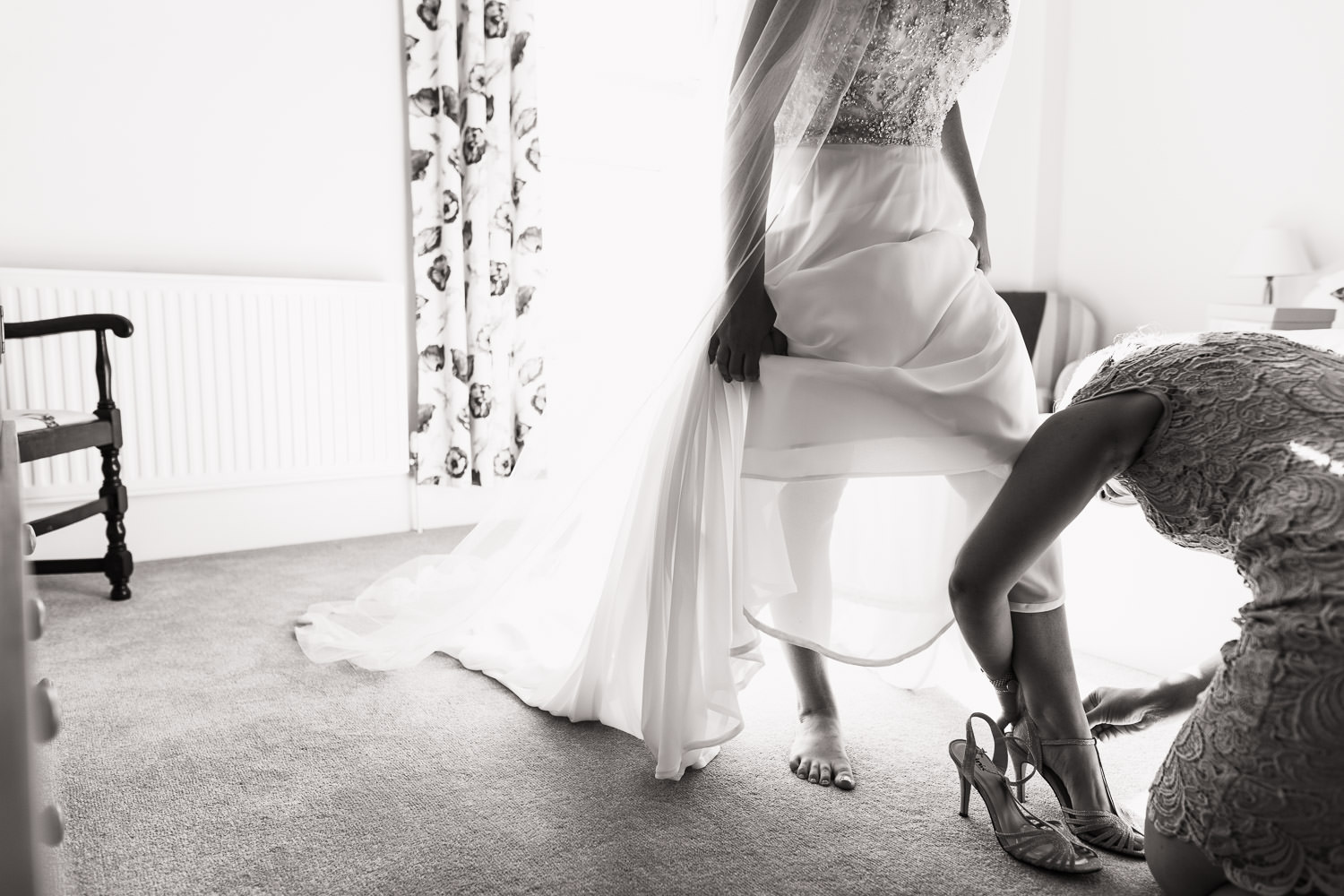 Bride putting on shoes with help from her sister