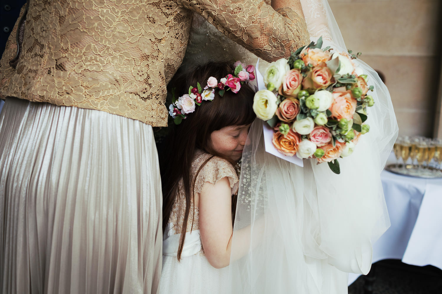 Flower girl hugging bride at London wedding
