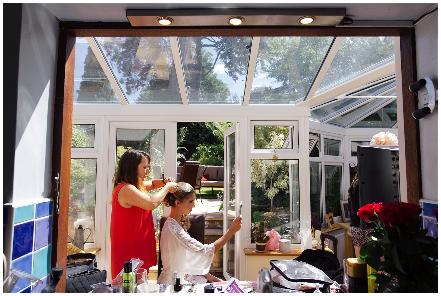 In a conservatory at home a woman is having her hair done.