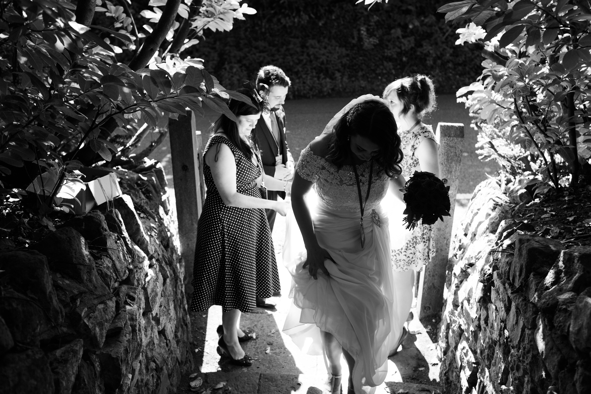 A woman in a wedding dress walking up stone steps to the family home, where her wedding reception will take place. In Chew Magna.