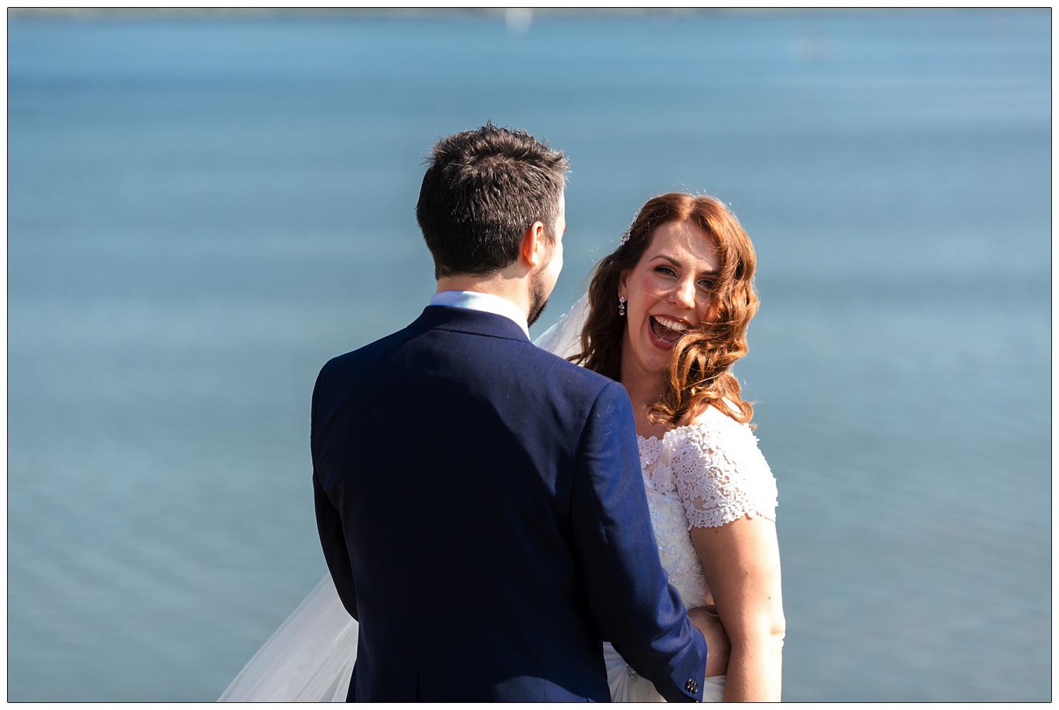 Bride and groom smiling with the Chew Valley lake in the background.