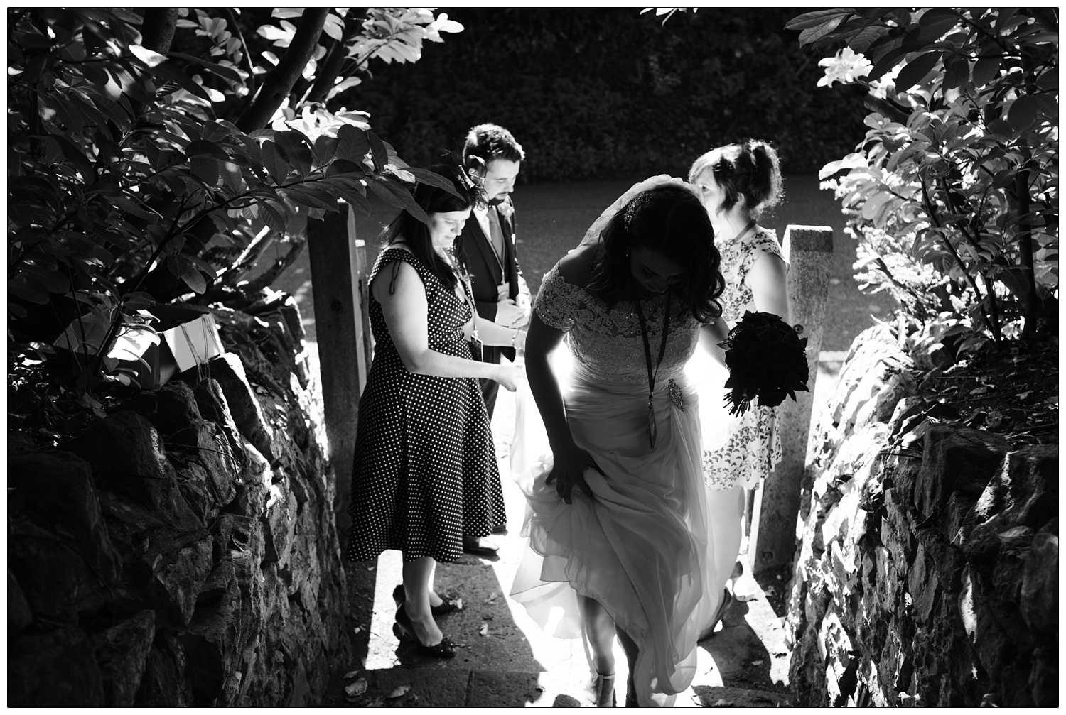 A woman in a wedding dress walking up stone steps to the family home, where her wedding reception will take place. In Chew Magna.