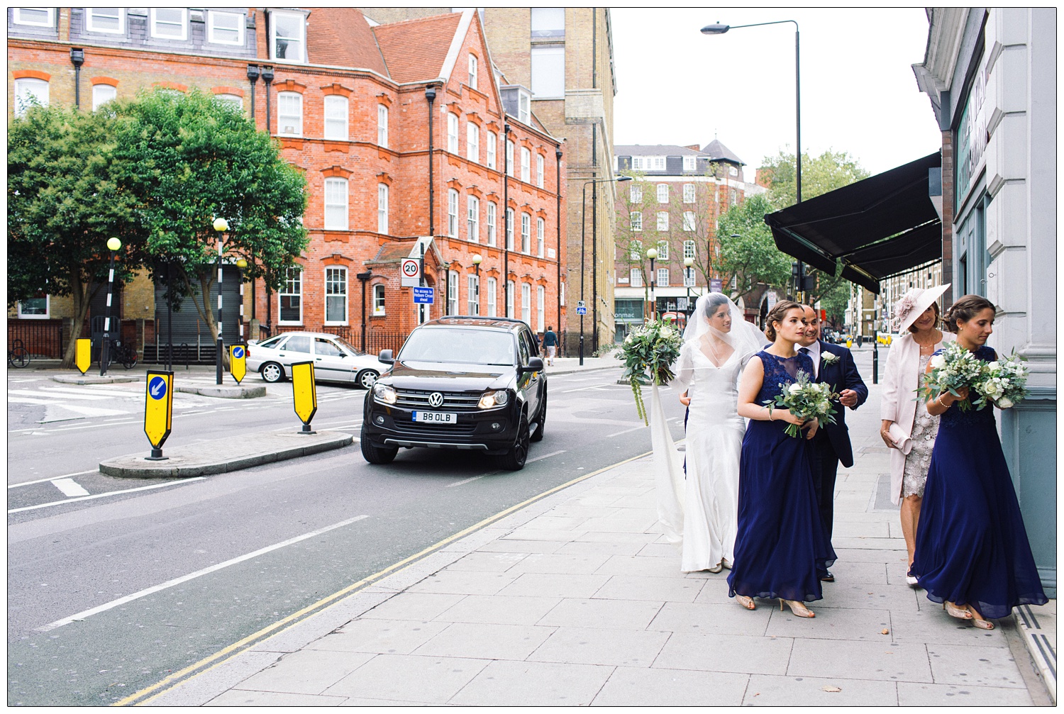 Bride and family and bridesmaids walking down Clerkenwell Road to the church.
