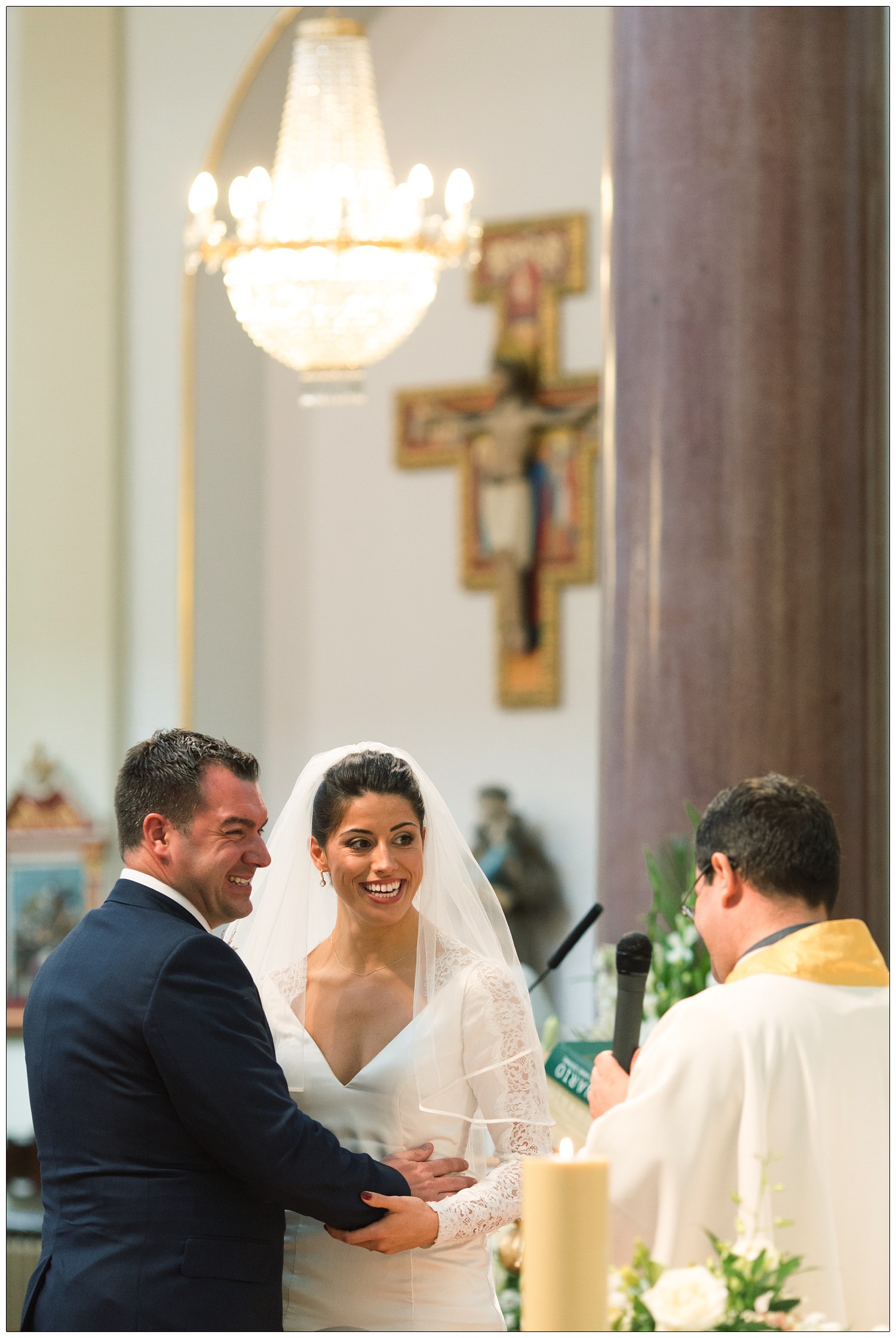 Bride and groom during the wedding ceremony in St. Peter's Italian Church in Clerkenwell. They are both smiling.