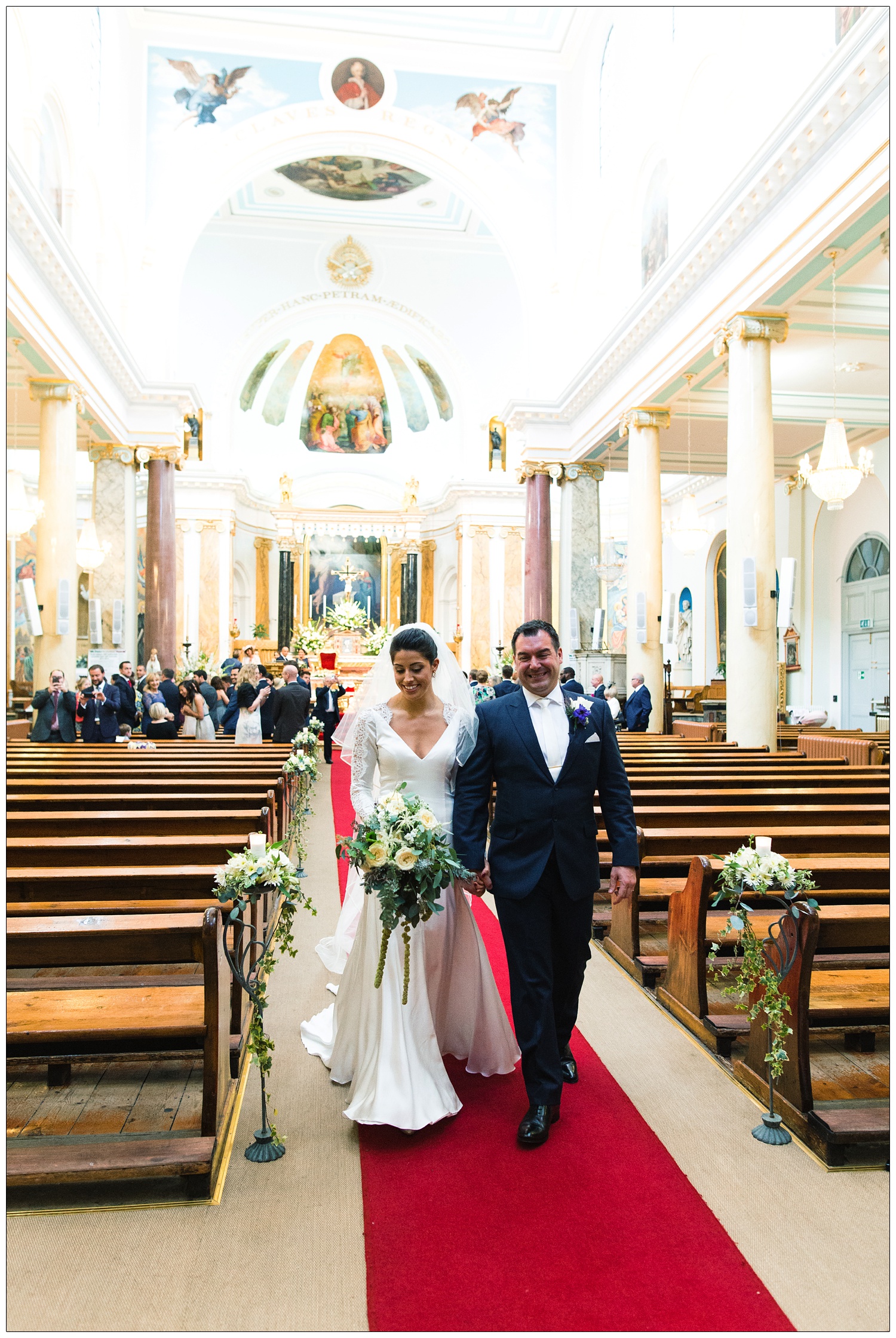 Woman and a man walking down the aisle after getting married in St. Peter's Italian Church in Clerkenwell.