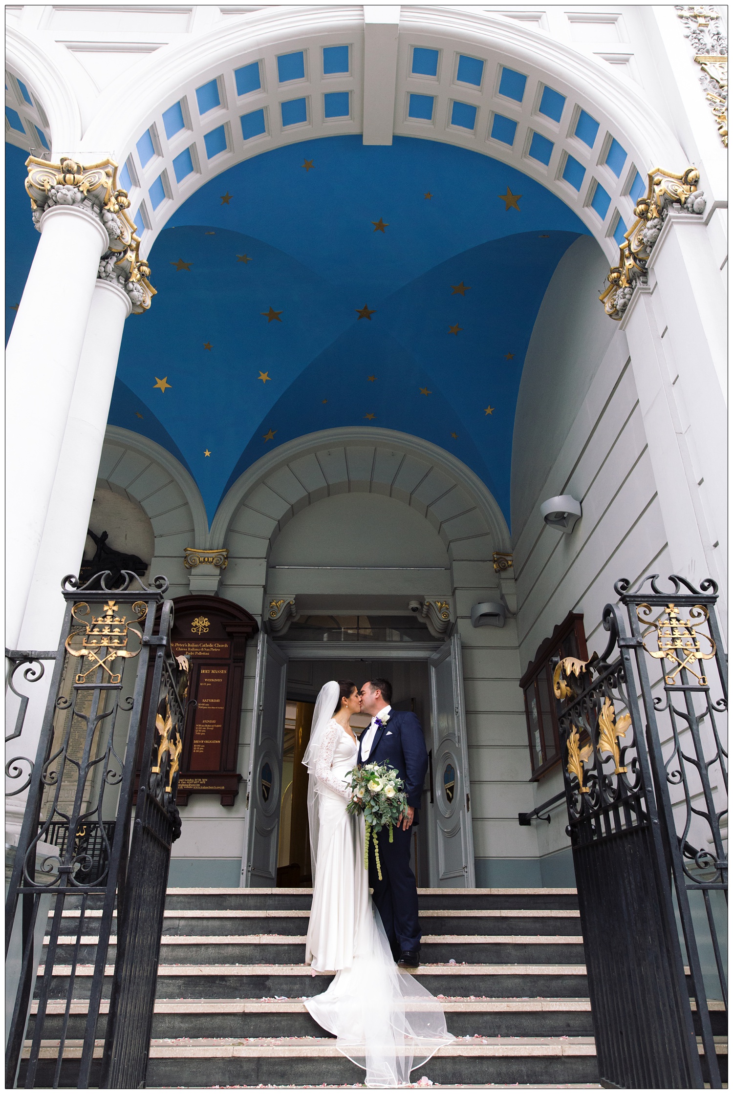 Bride and groom kiss on the steps of St. Peter's Italian Church in Clerkenwell.