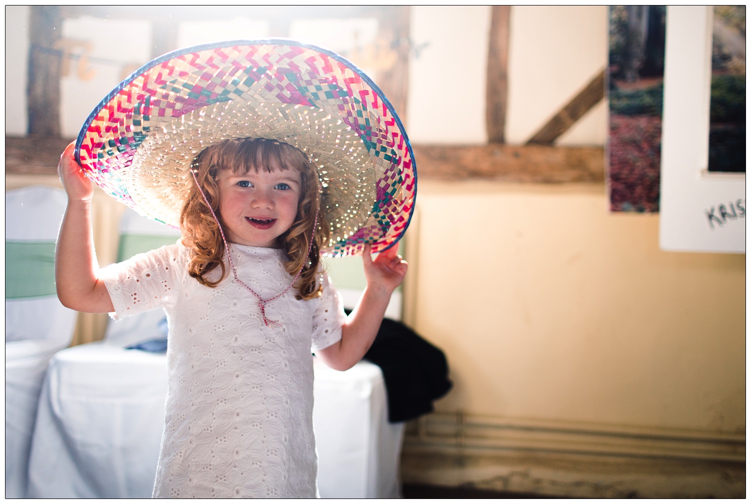 A girl trying on a big hat from a dressing up box.