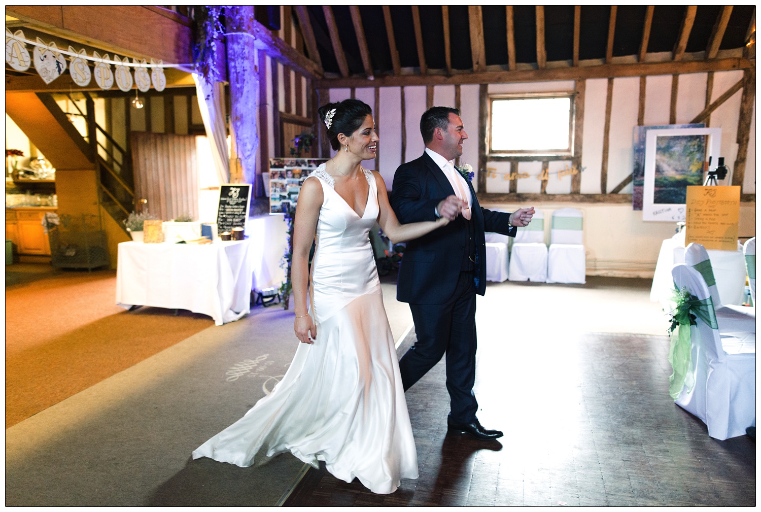 A bride in her long elegant satin silk dress enters the barn with her husband.