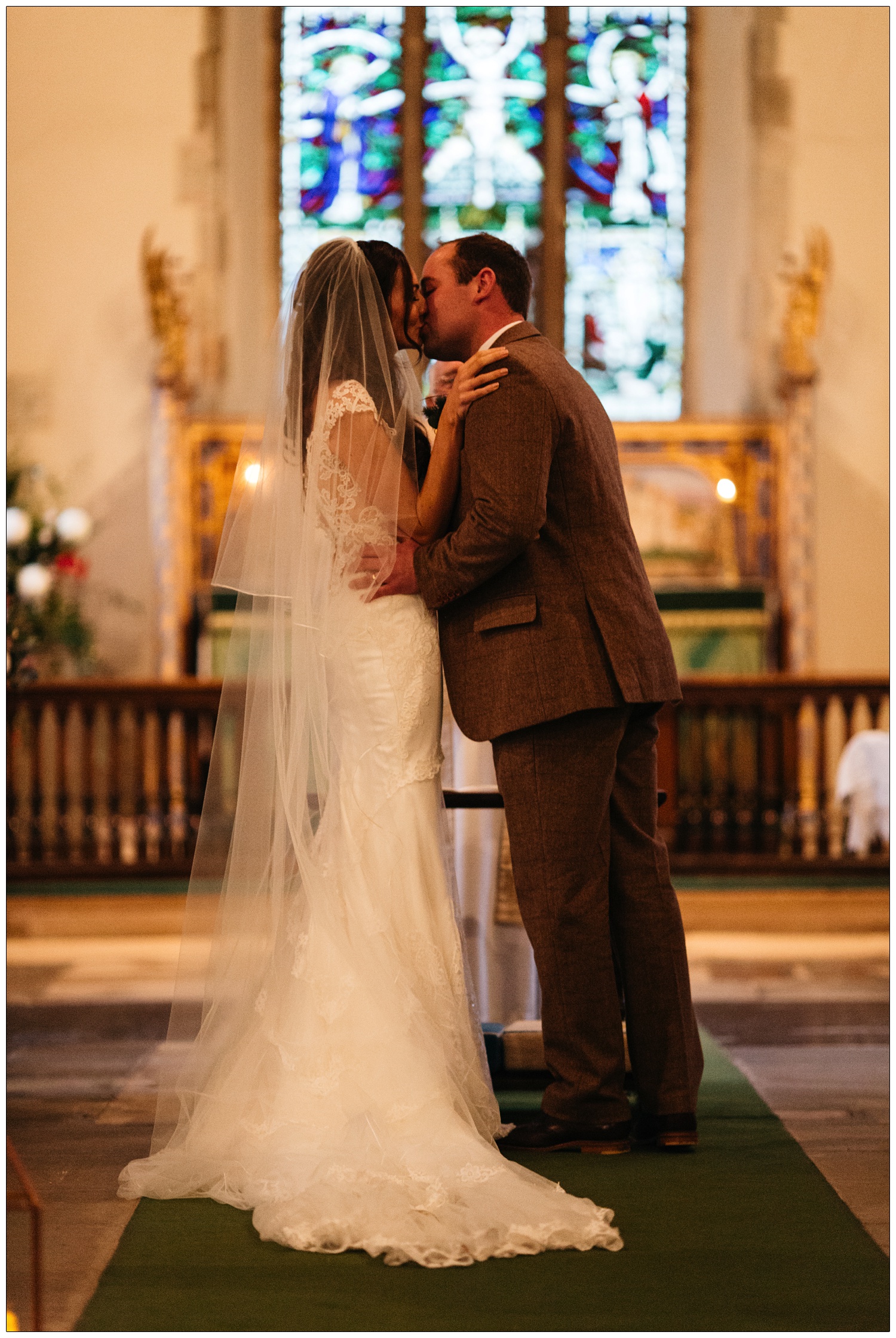 A couple kiss in a winter wedding ceremony at All Saints Church in Purleigh.
