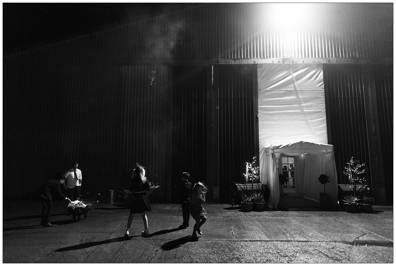 Outside the barn there is a fire pit and children are running about.