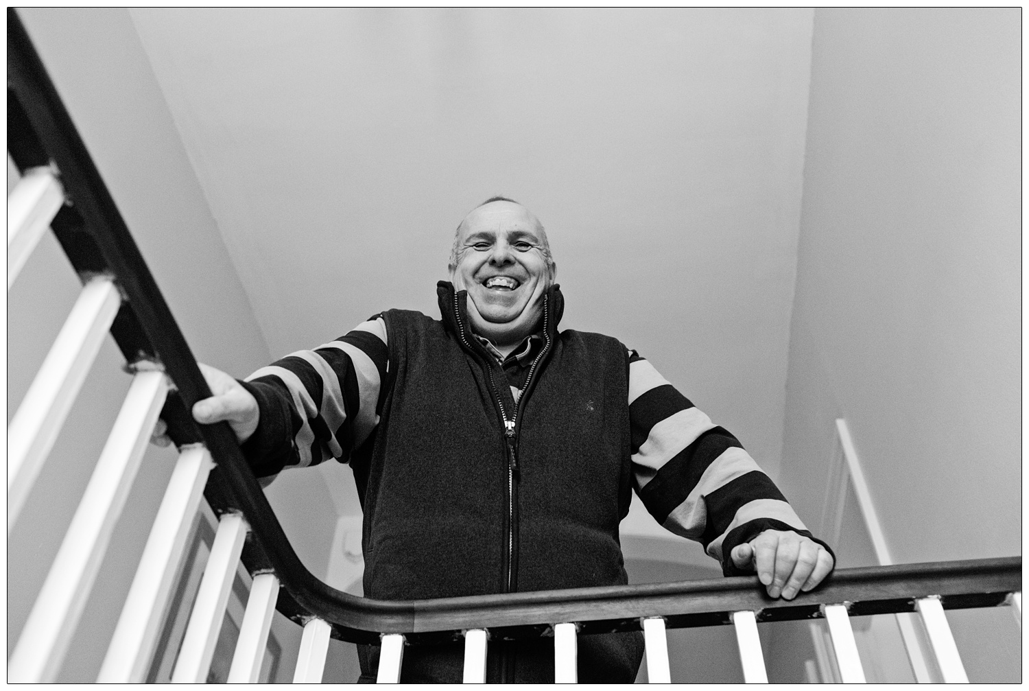 Father of the bride leans over the stairs bannister.