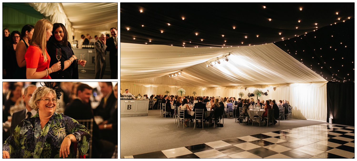 A view of the barn decorated for a wedding. There is a black and white chequered floor, a black ceiling with small lights. Fabric is draped on the walls and above the tables where the wedding guests are sat for dinner.