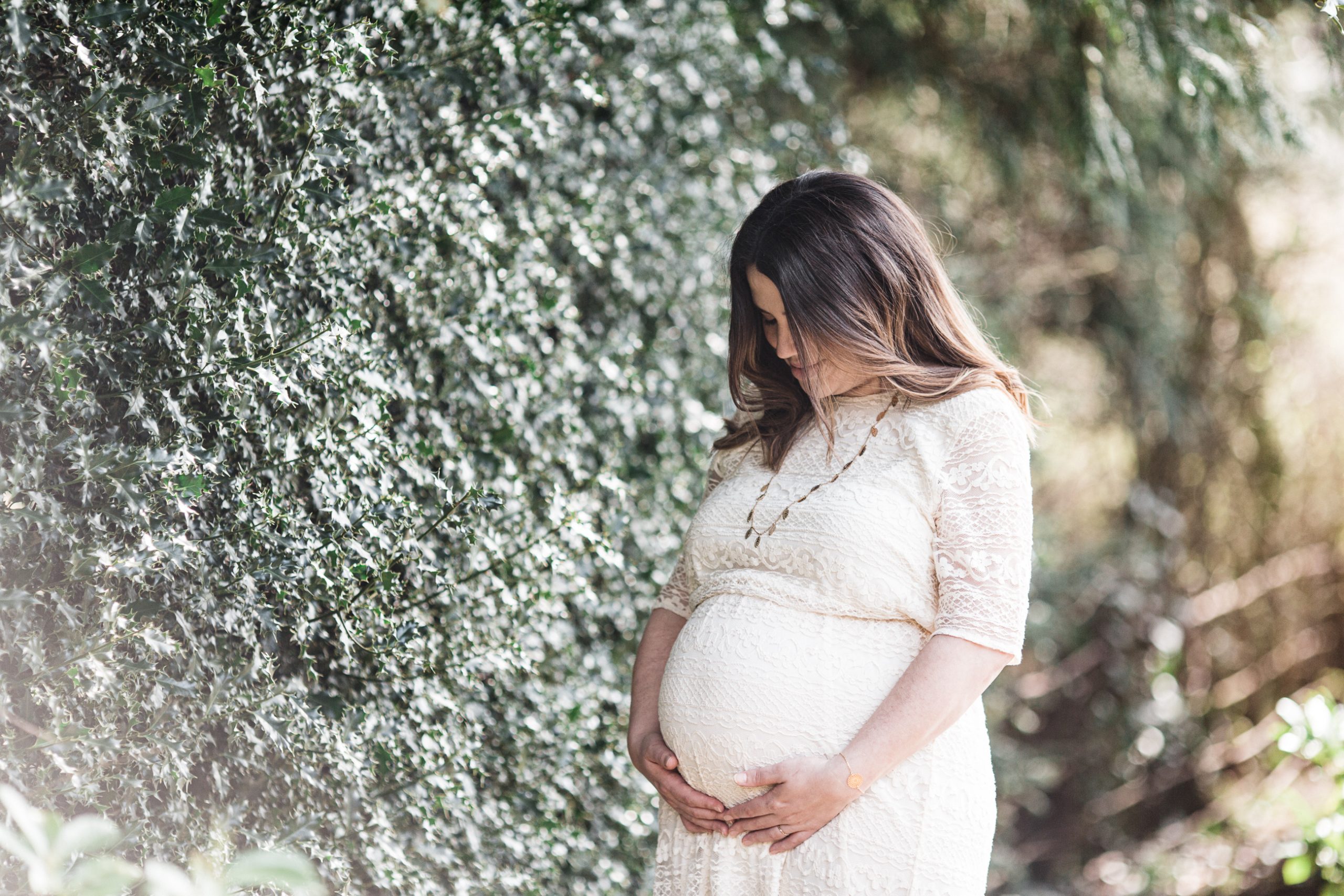 Maternity photography of a woman holding her bump outside