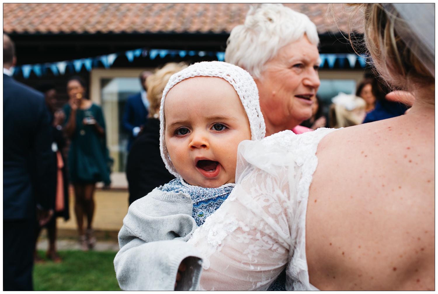 baby yawning whilst being held by her mum at wedding