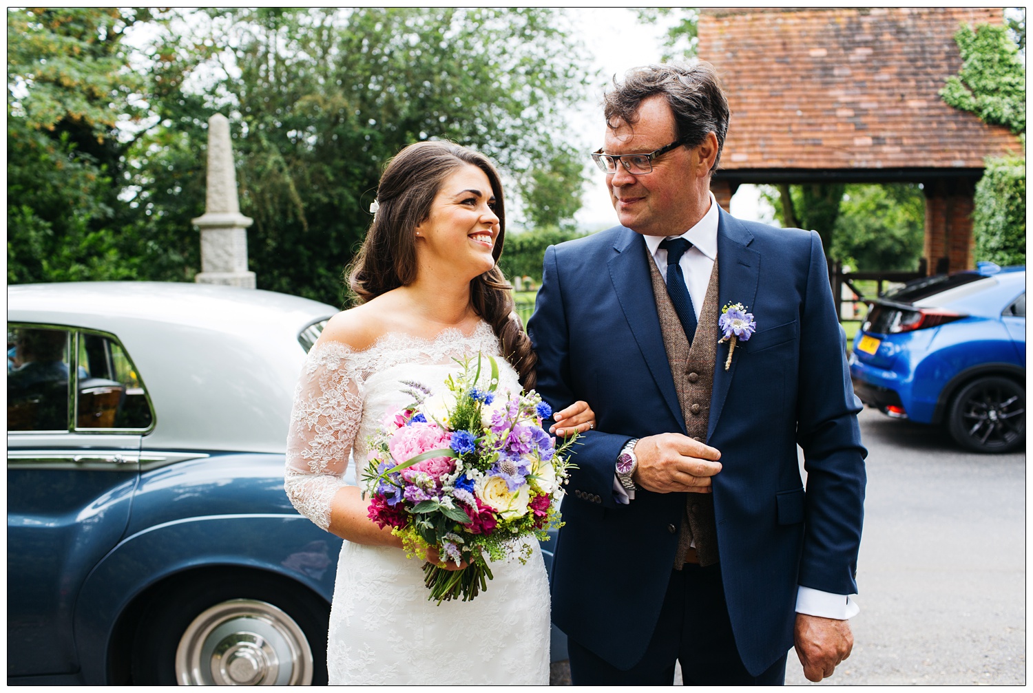 woman in wedding dress looks at her dad outside the All Saints church in Purleigh