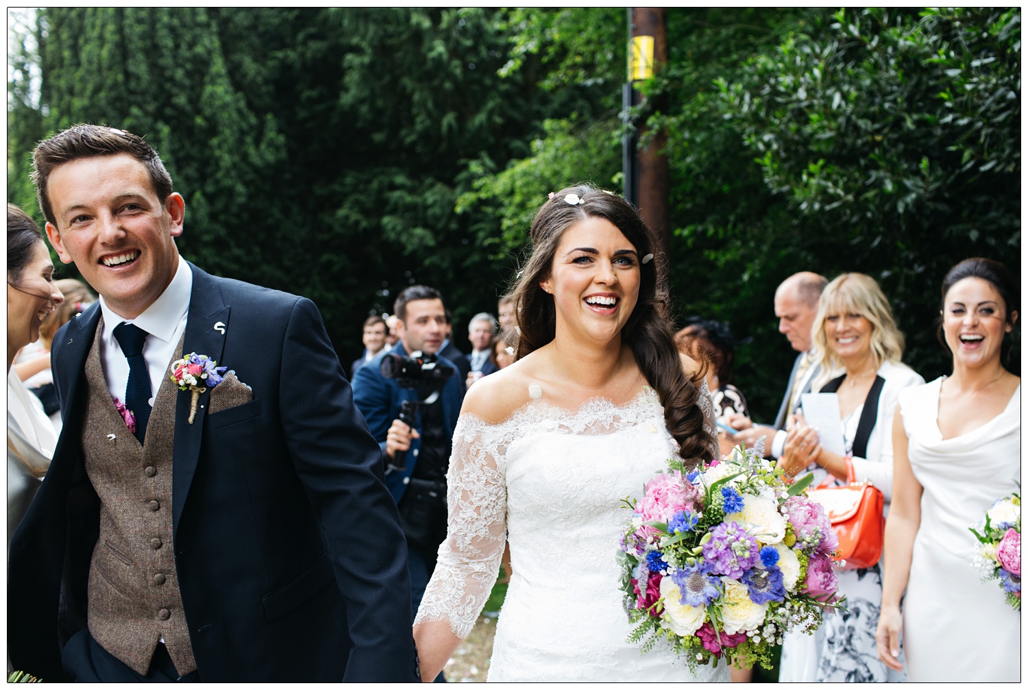 bride and groom walking through confetti and laughing in Purleigh Essex