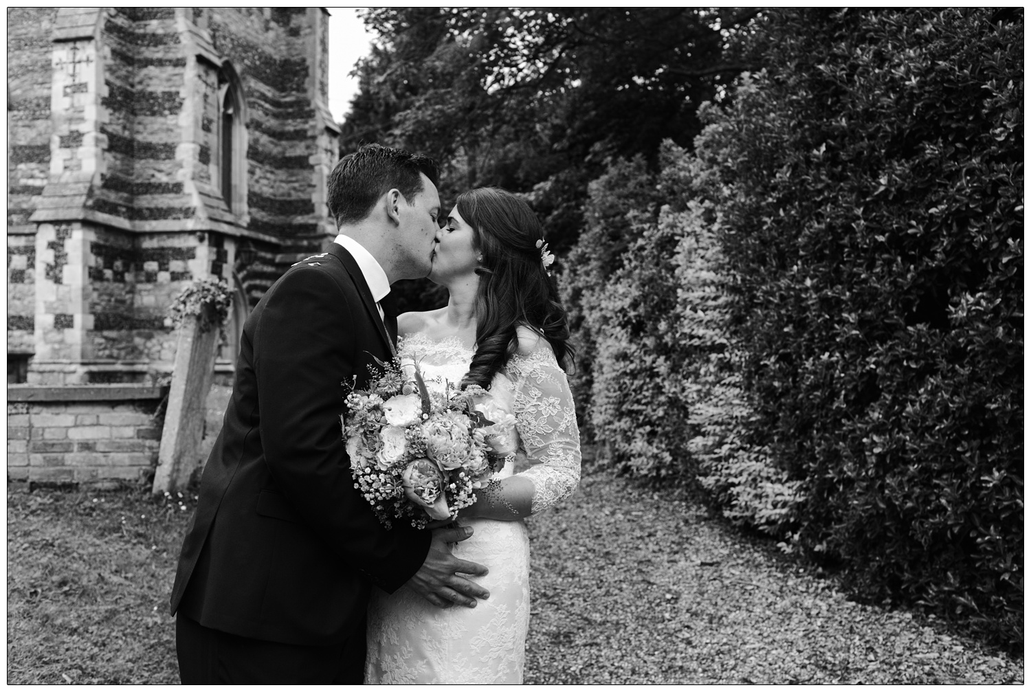newly wed couple kissing outside All Saints church in Purleigh