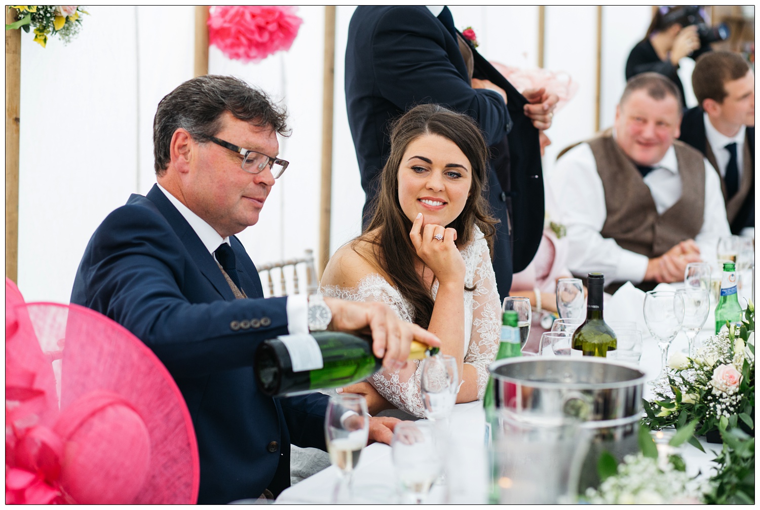 woman in wedding dress watching dad pour a drink