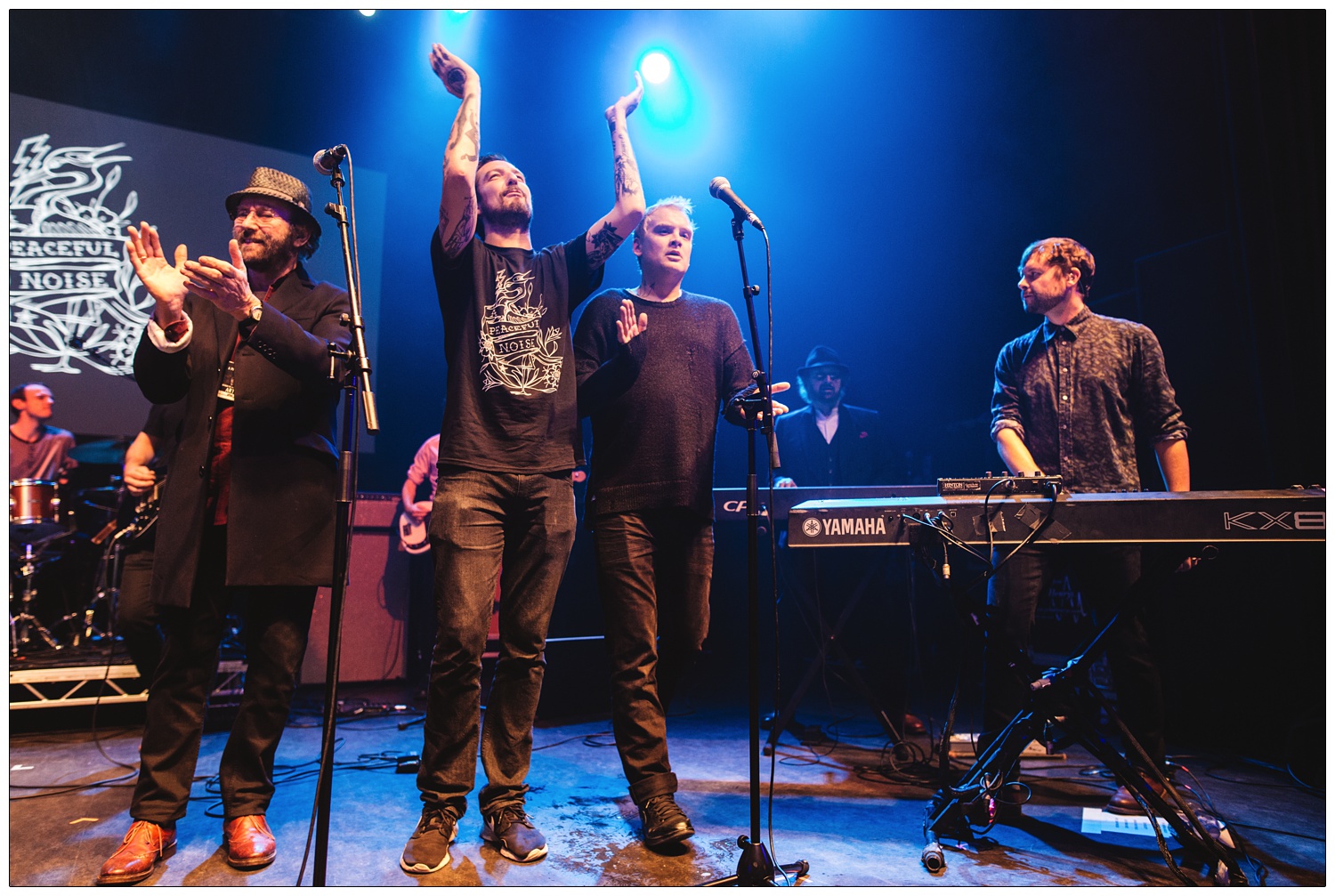 Lukas Wooller and Chas Hodges behind keyboards and Dave Peacock and Frank Turner clapping at A Peaceful Noise gig