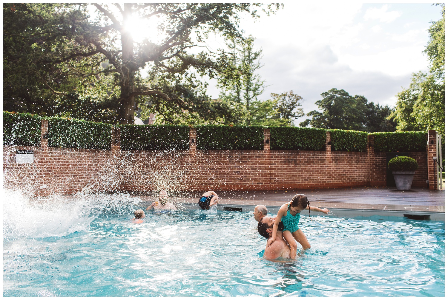 daughter and dad playing with other wedding guests in the pool at Maison Talbooth near Colchester