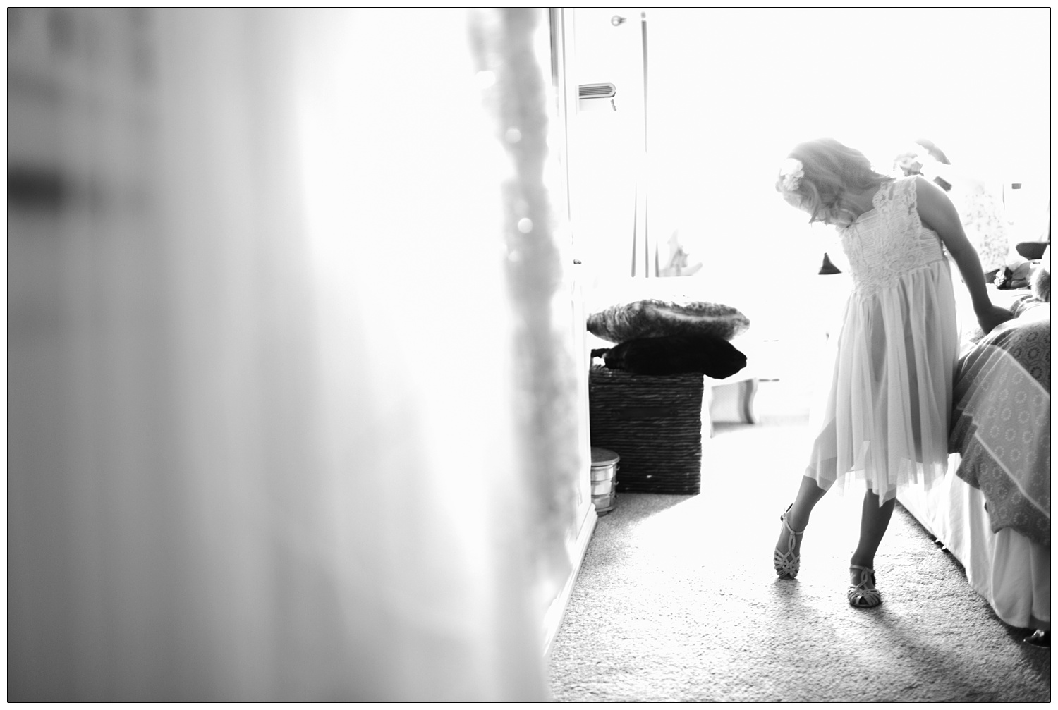 black and white photograph of flower girl looking back at her shoe