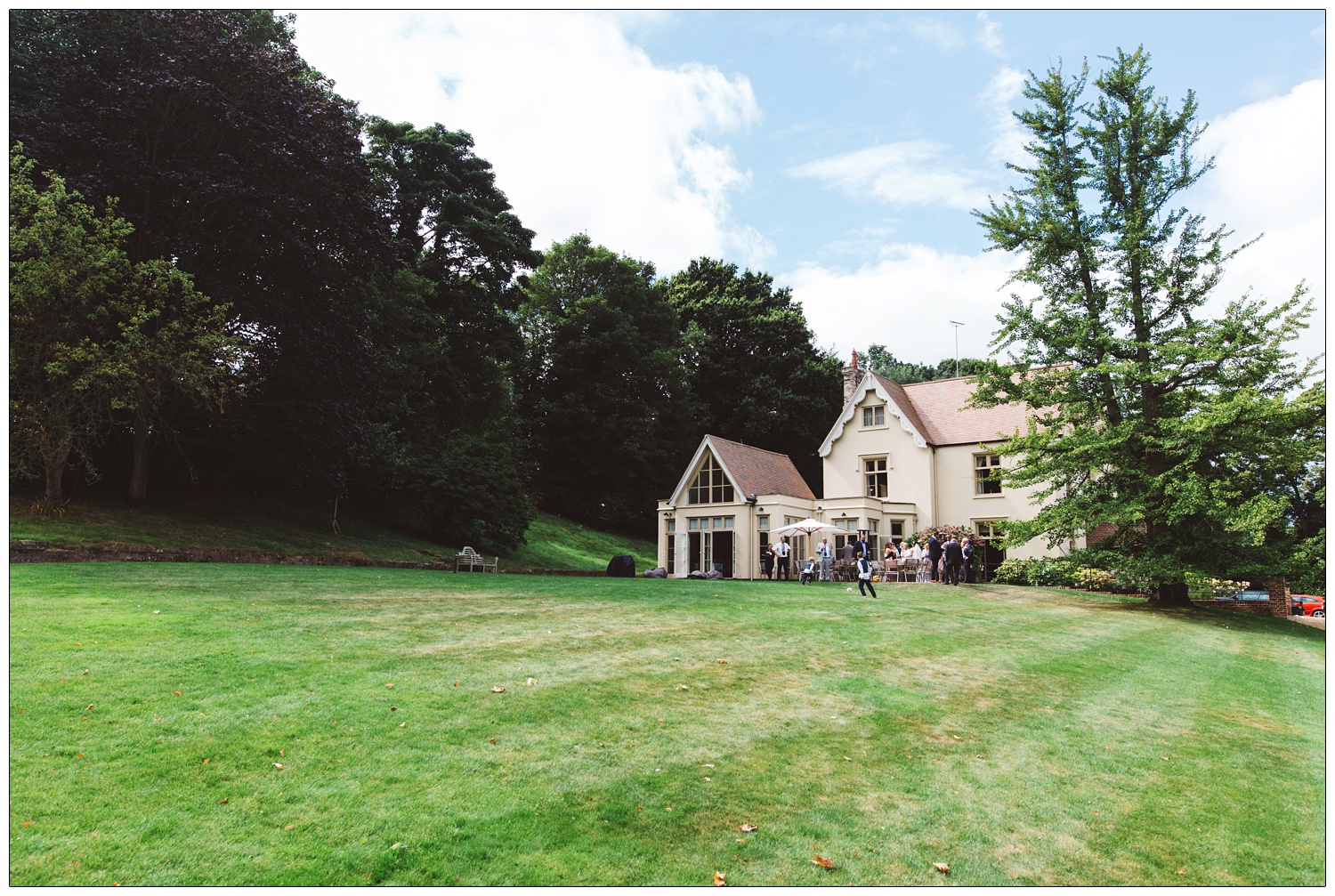 wedding guests outside Maison Talbooth near Colchester, the sky is blue