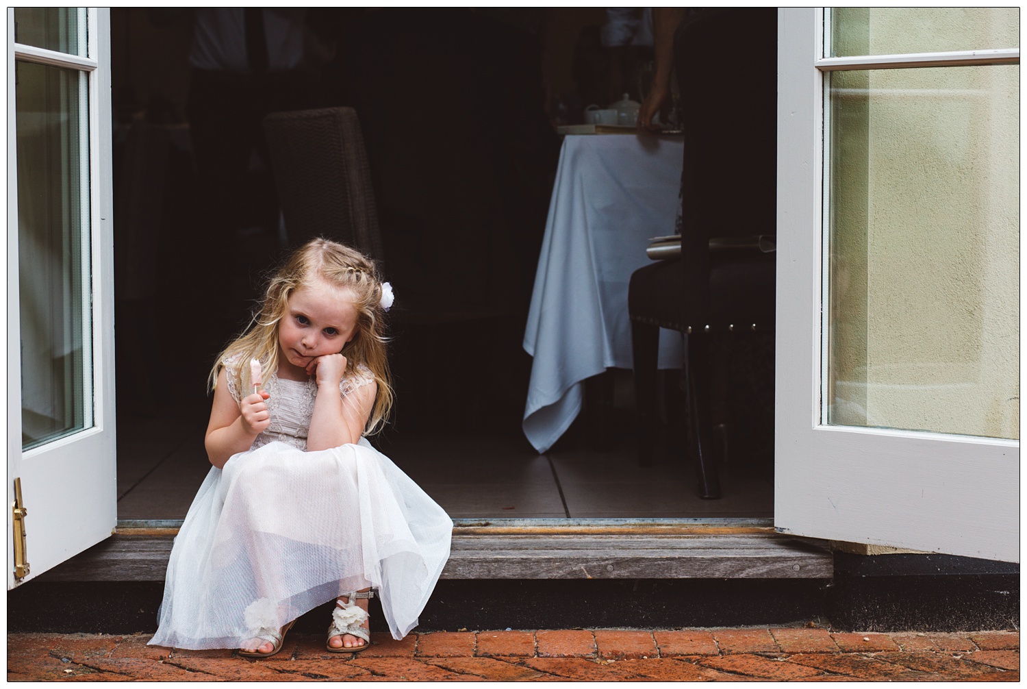 flower girl eating a drumstick lolly say on a step