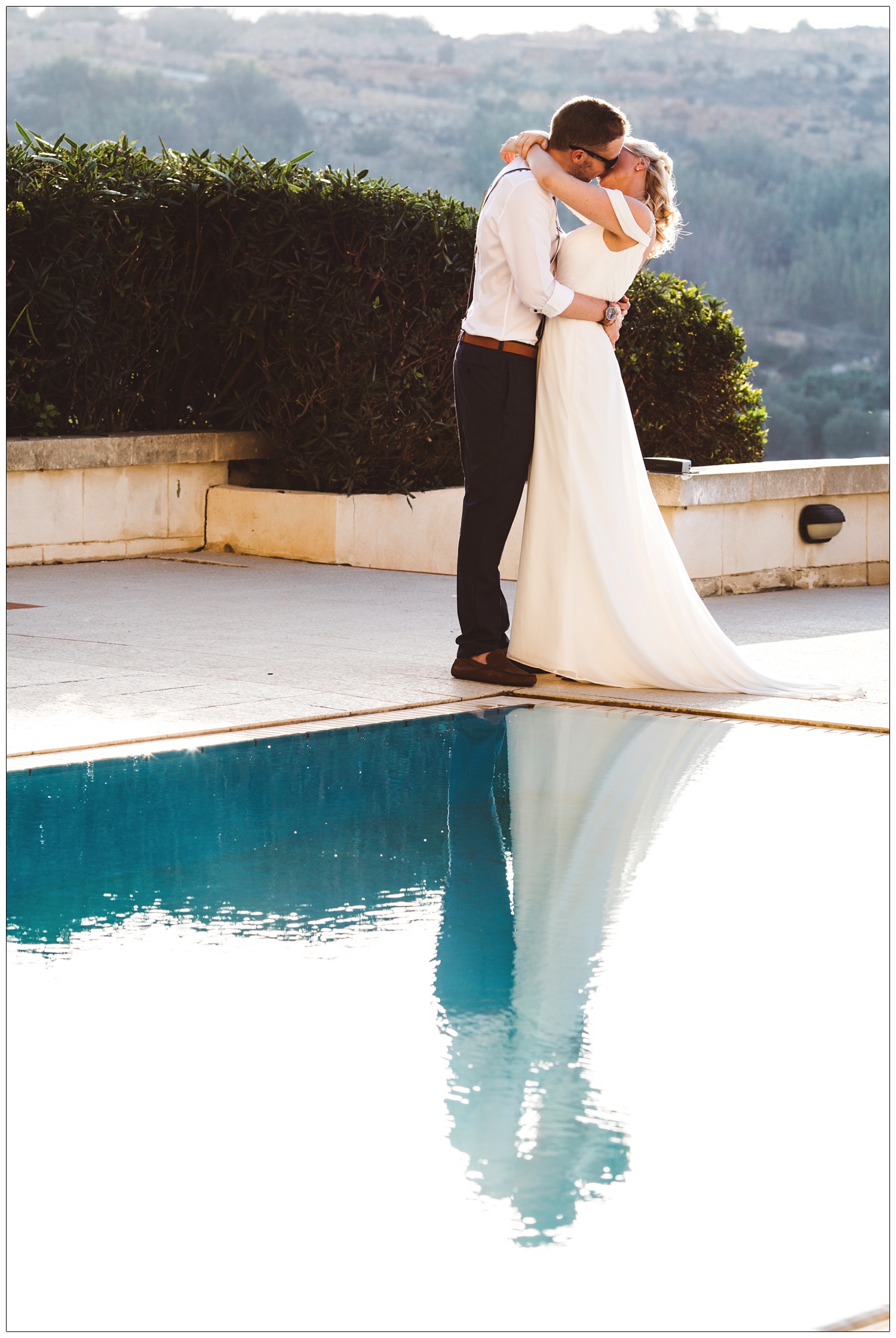 bride and groom kissing and reflected in the pool The Cornucopia Hotel in Gozo after getting married