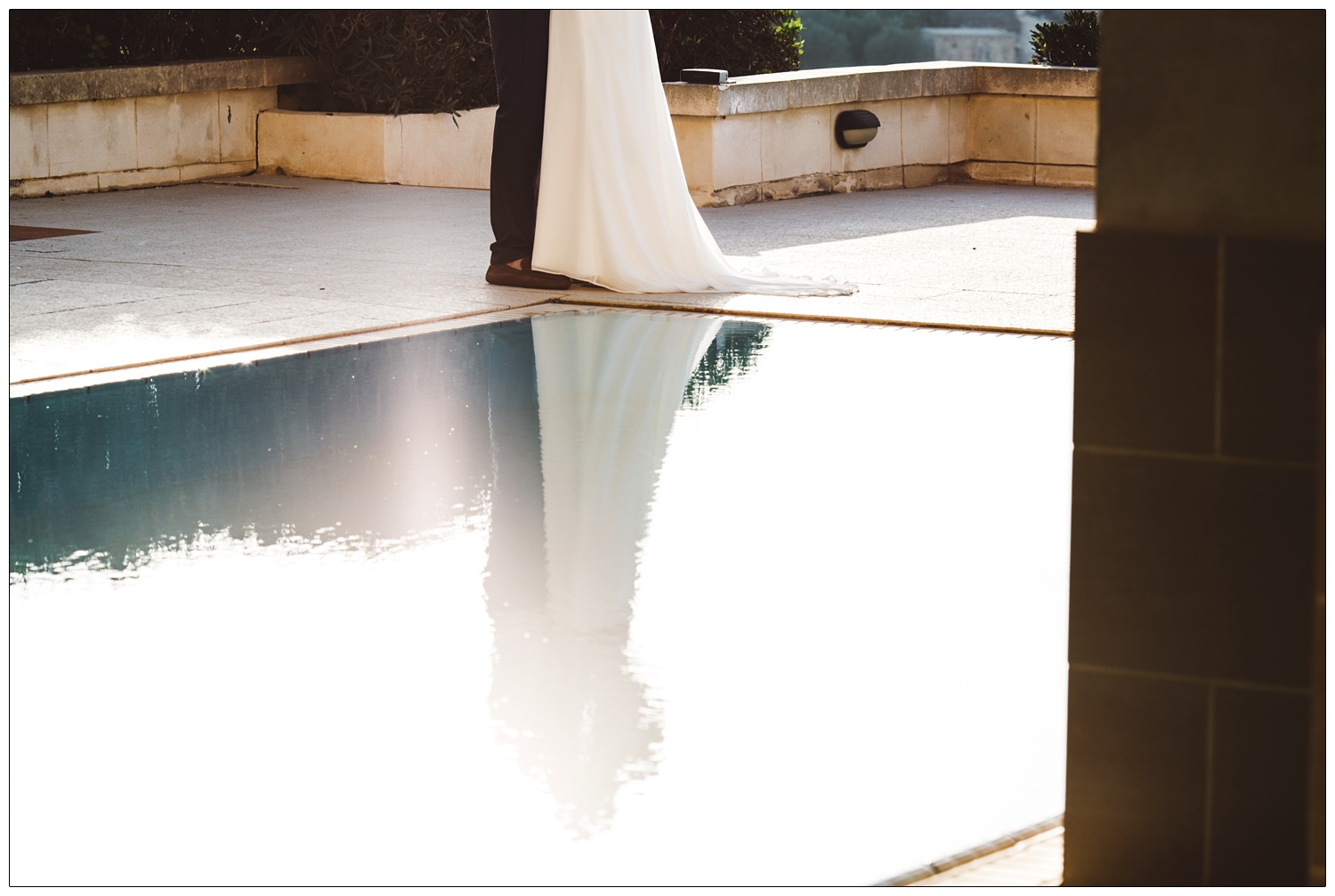 Bride and groom reflected in water.