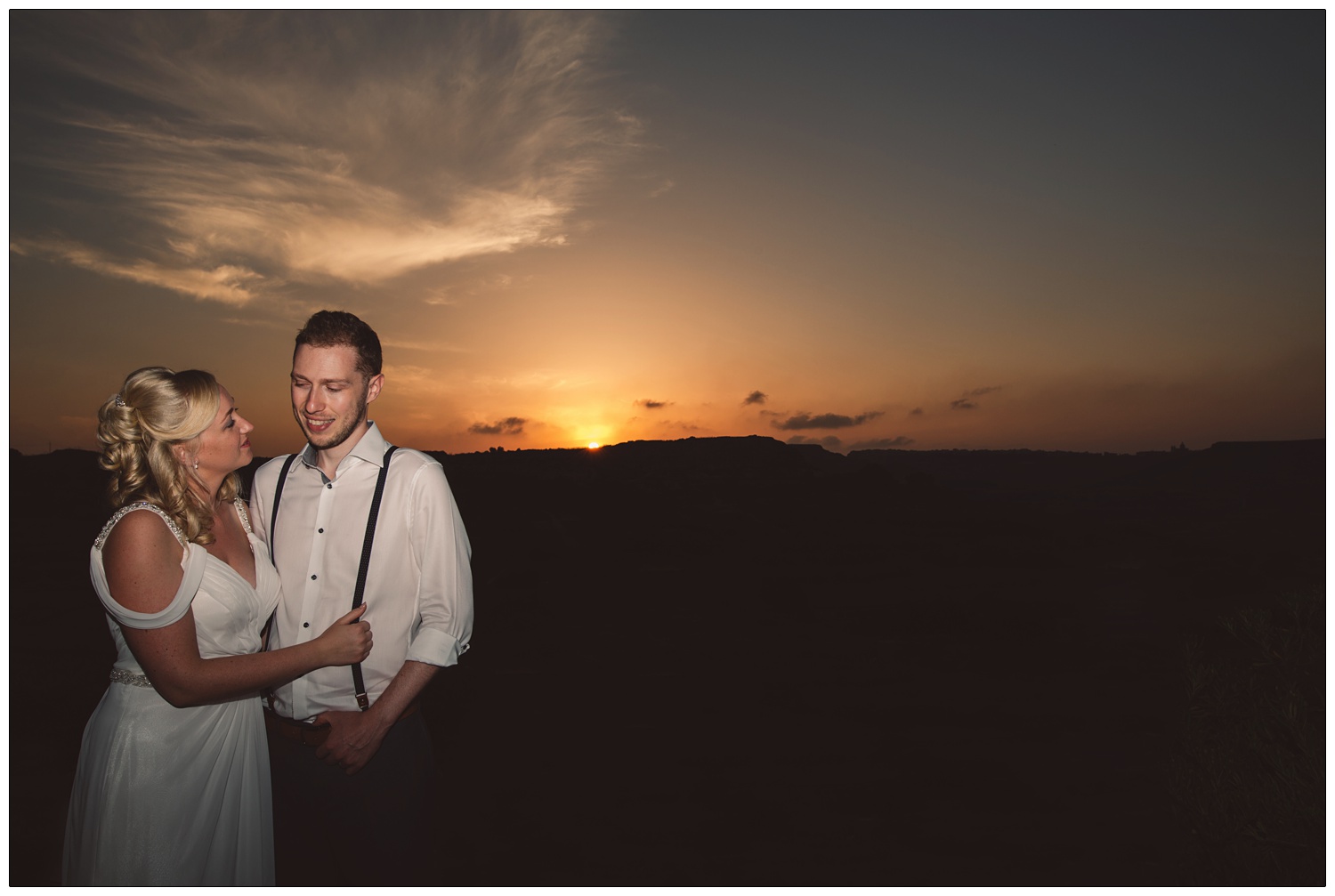 bride and groom in front of a sunset