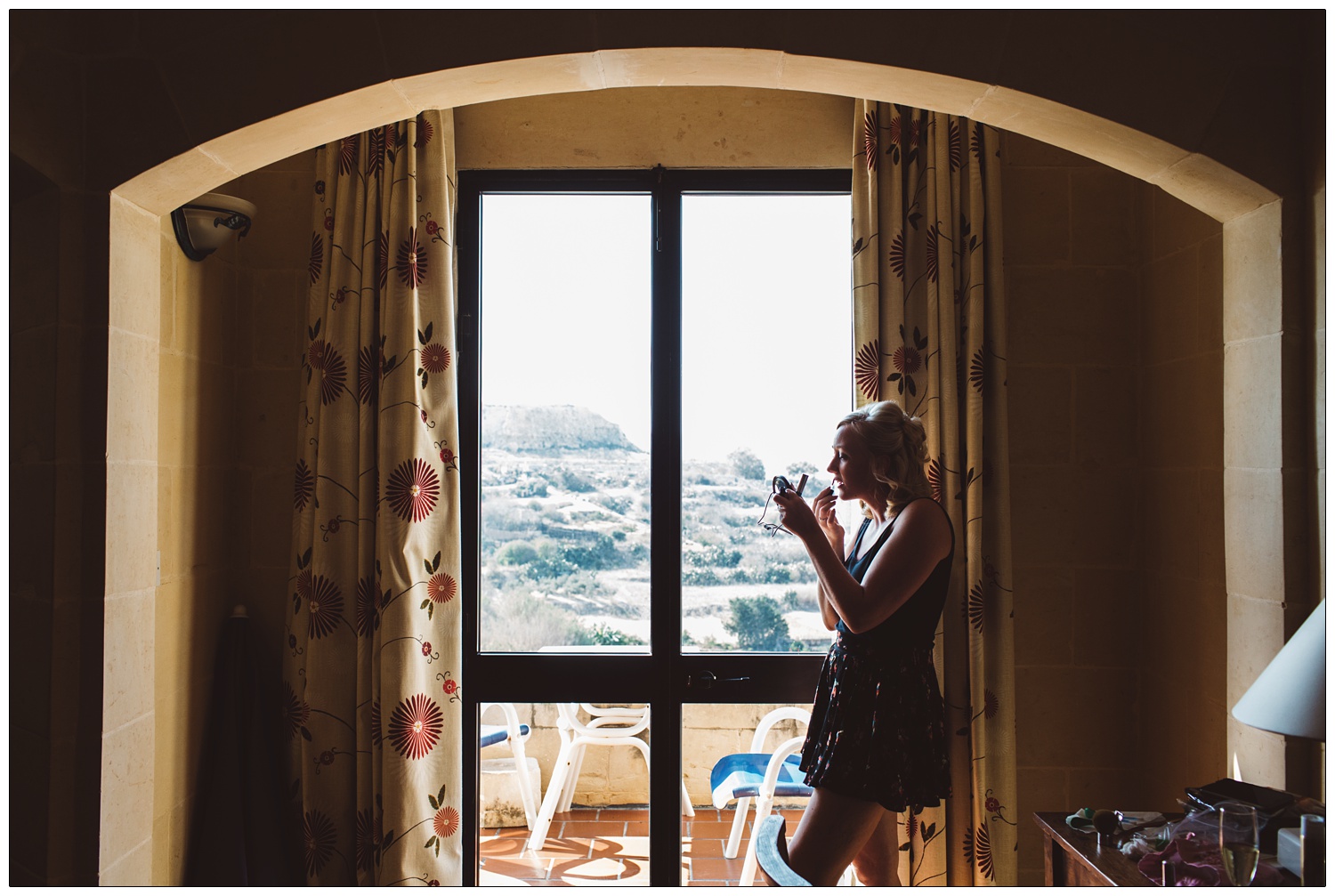 bride getting ready and applying make up in the door of her hotel room