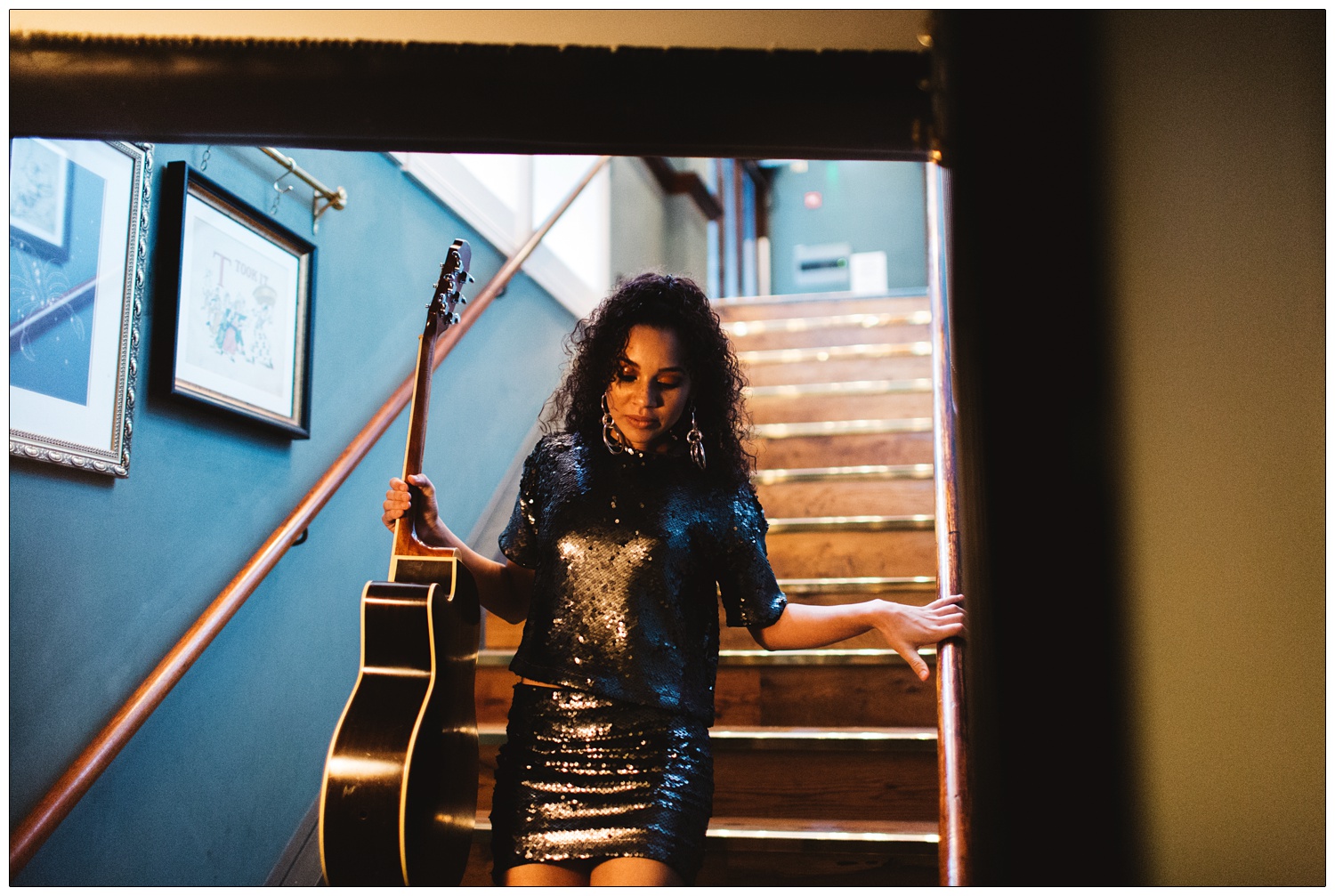 Singer Malaika coming down the stairs holding a guitar
