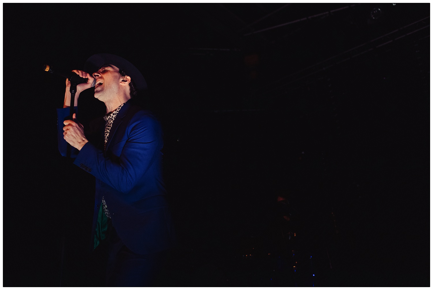 Paul smith singing in a blue suit, black hat, and leopard print shirt